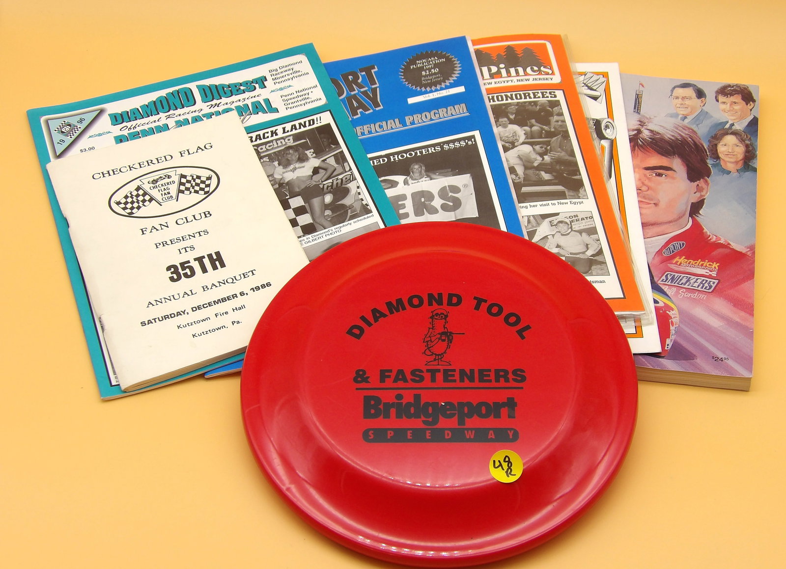 Racing Magazines & Frisbee: This vintage racing lot includes Checkered Flag Fan Club 35th Annual (1985) Banquet Program, Clyde Martin Speedway Program (2000), Thunder In The Pines, Bridgeport Bandit, Bridgeport Speedway,