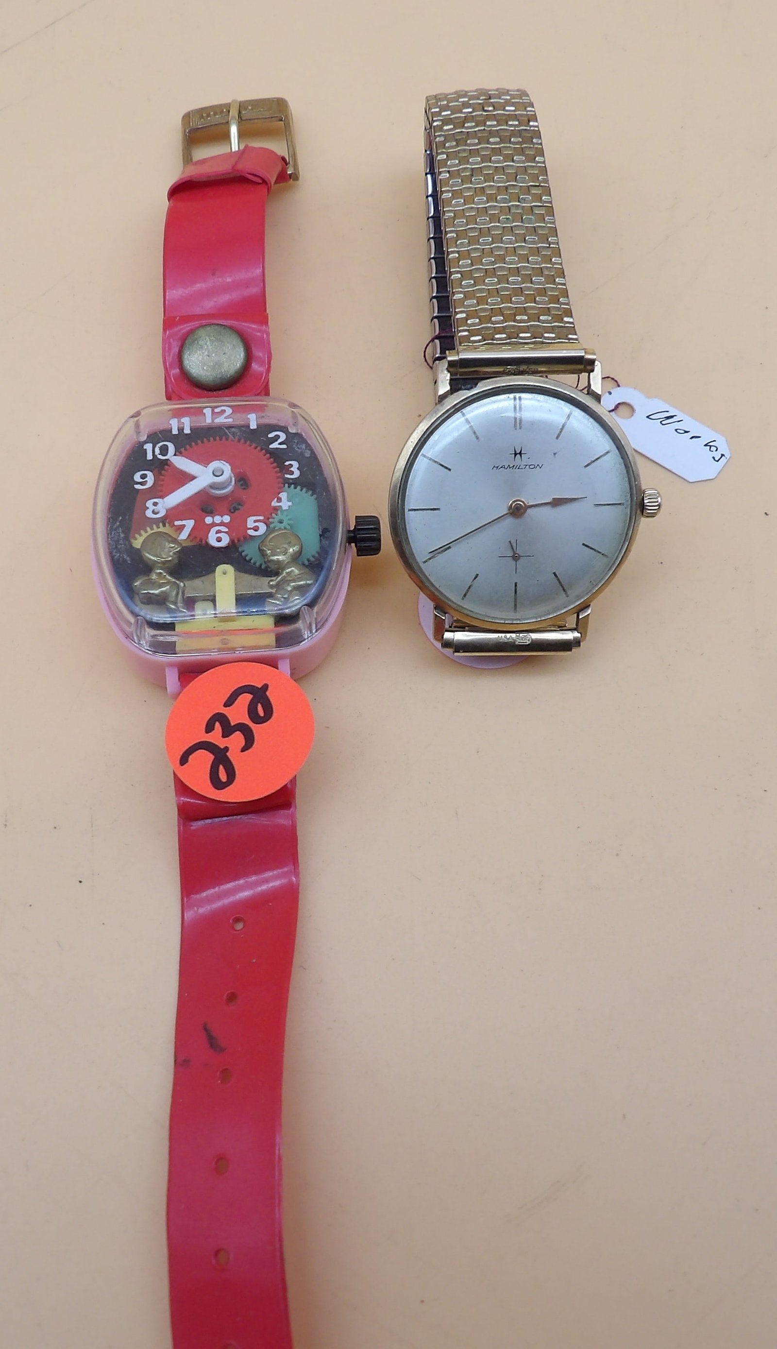 Merry Wind Up Teeter Totter Watch & Hamilton Masterpeice Watch: This pair of vintage watches includes a 1970's Merry Wind Up Teeter Totter Red Band Watch and a 1960's Hamilton Masterpeice Watch w/ 14k gold casing. Measures 8.5" and 4.5"