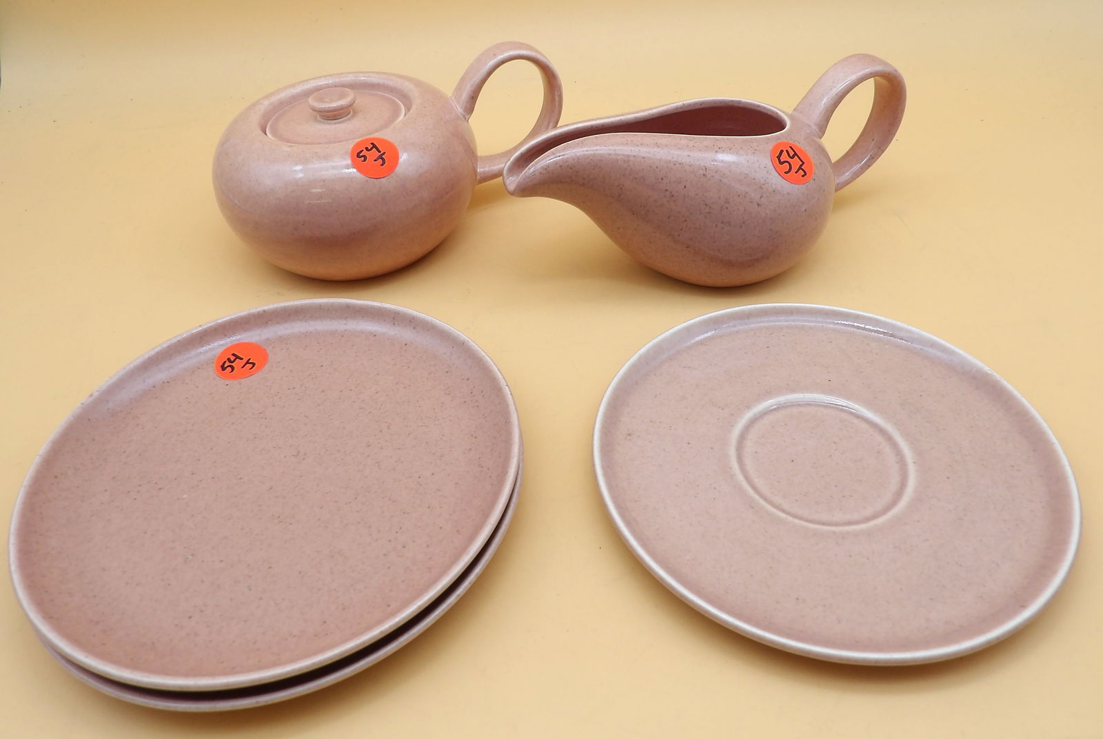 Russel Wright Lidded Sugar Bowl, Creamer, Saucer, Plates: This fabulous vintage Russel Wright lot includes a lidded sugar bowl, a creamer, a saucer, and 2 plates - all in 'Coral' color. Measures: 3" x 6" x 4.5" // 3" x 7.5" x 4" and 6".