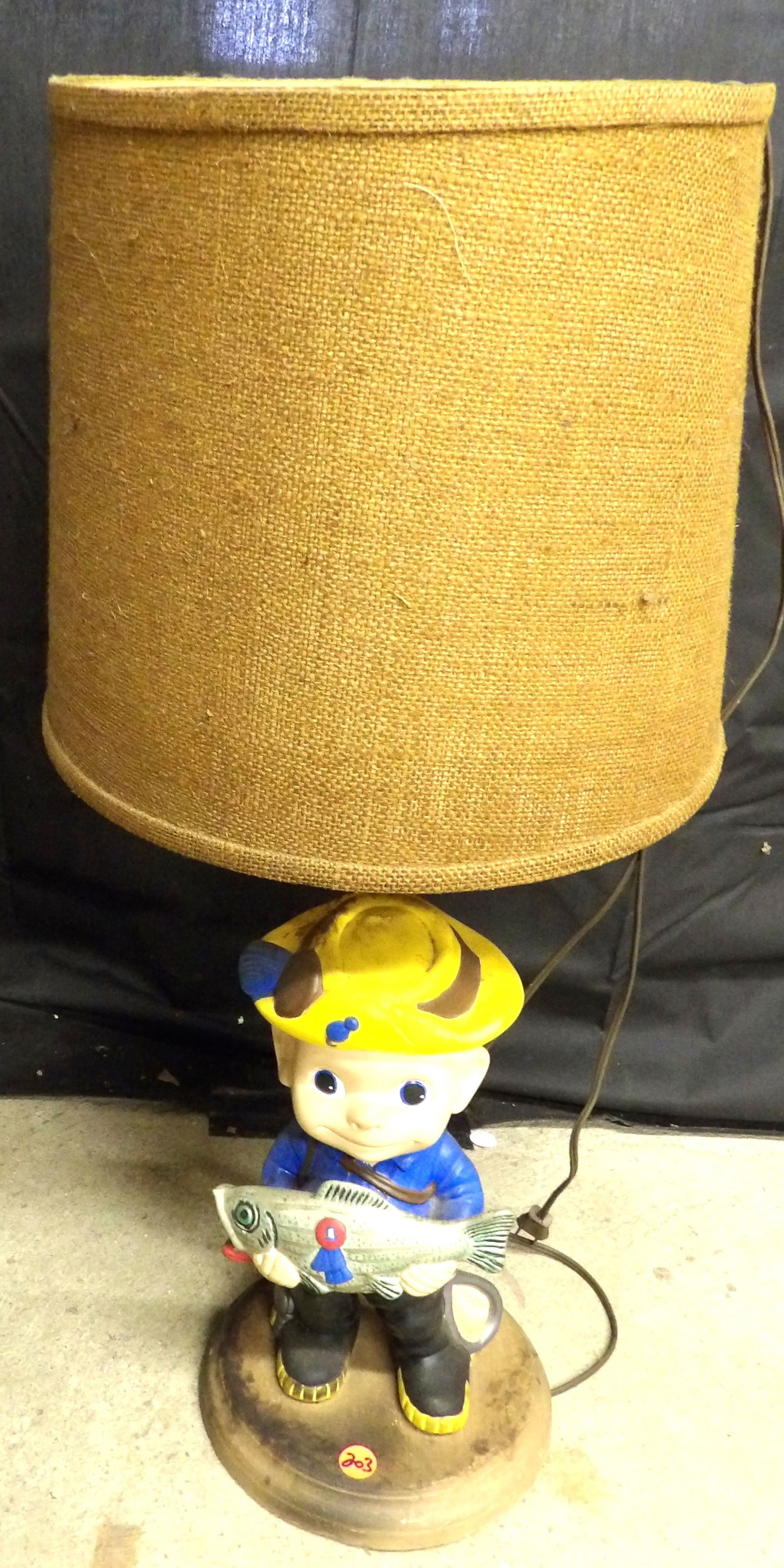 "Prize Fish" Porcelain Lamp: This porcelain lamp is mounted on a wooden base and depicts a boy proudly displaying a "prize fish". Measures 27". NOTE: NO SHIPPING ON THIS ITEM