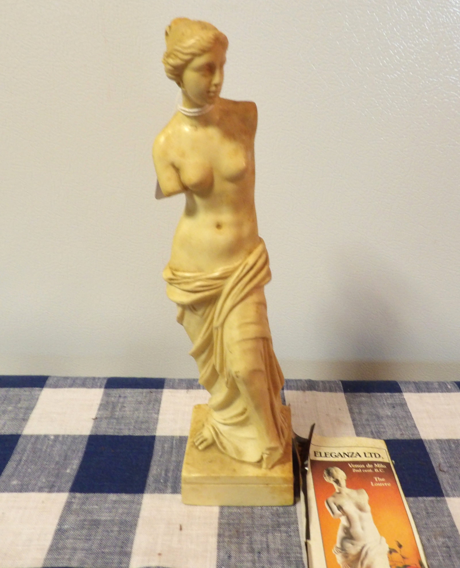 Venus de Milo Statue: This reproduction of the world famous classic Venus de Milo statue includes advertising newspaper clipping. Measures 11.5 x 2.75 x 2.75.
