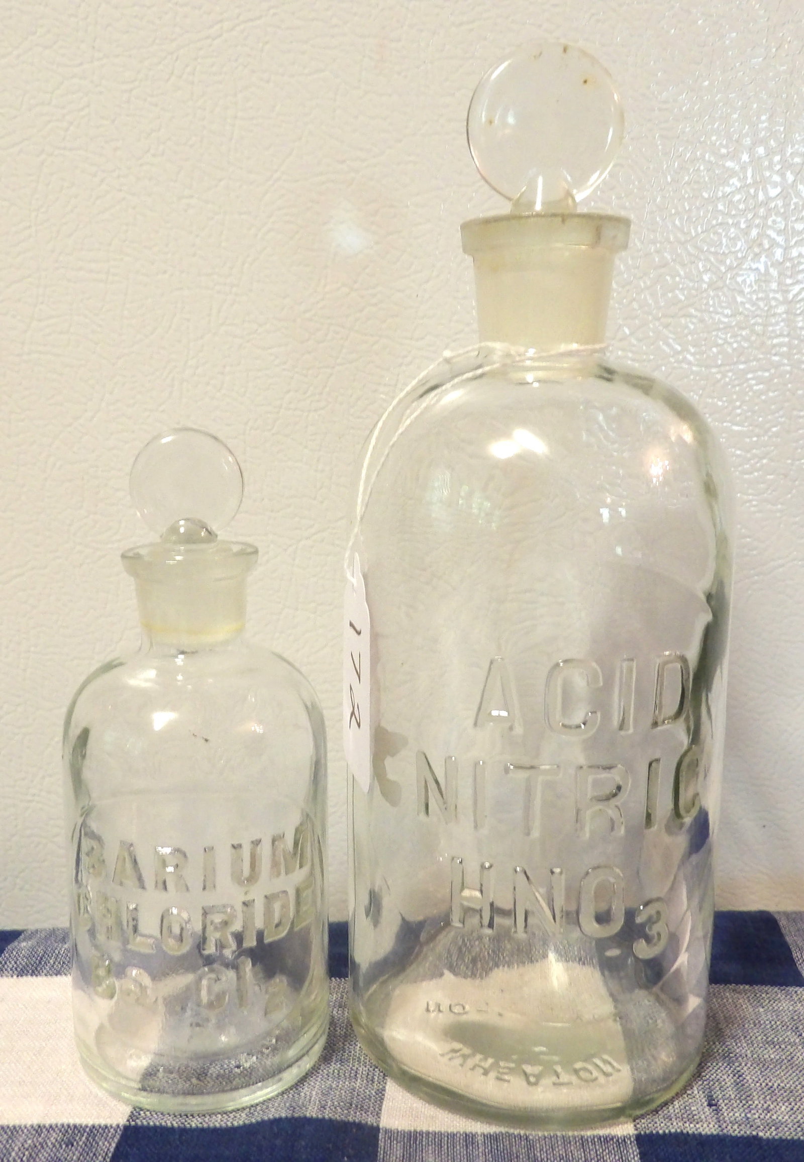 Glass Chemical Bottles (2) -: This pair of glass bottles are imprinted with the names of chemicals which they are meant to store - "Acid Nitric" , "Barium Chloride ". Measures 8" , 5.5"
