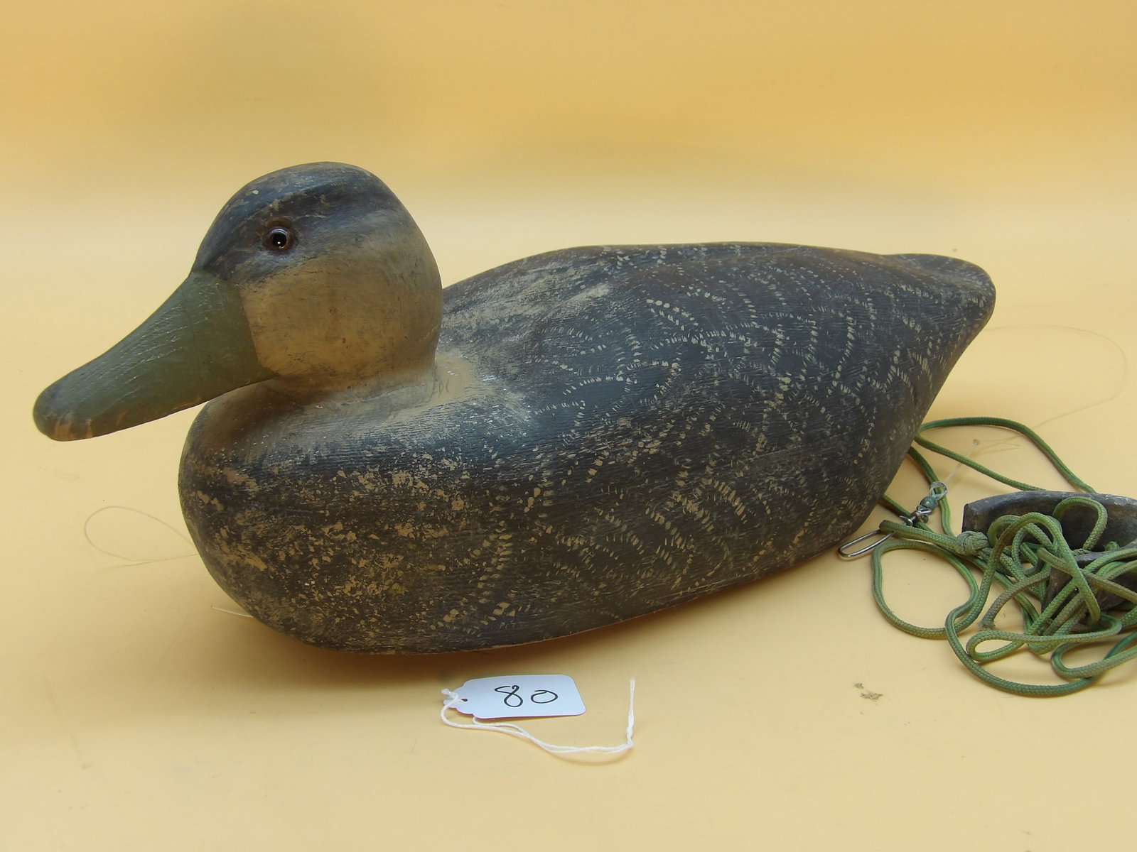 "American Black Duck" Wood Carved Metzger Decoy: This detailed wood carved duck decoy was created by renowned area decoy artist Lawrence Metzger. Includes lead line and weight. Measures approx: 7" x 17" x 6"