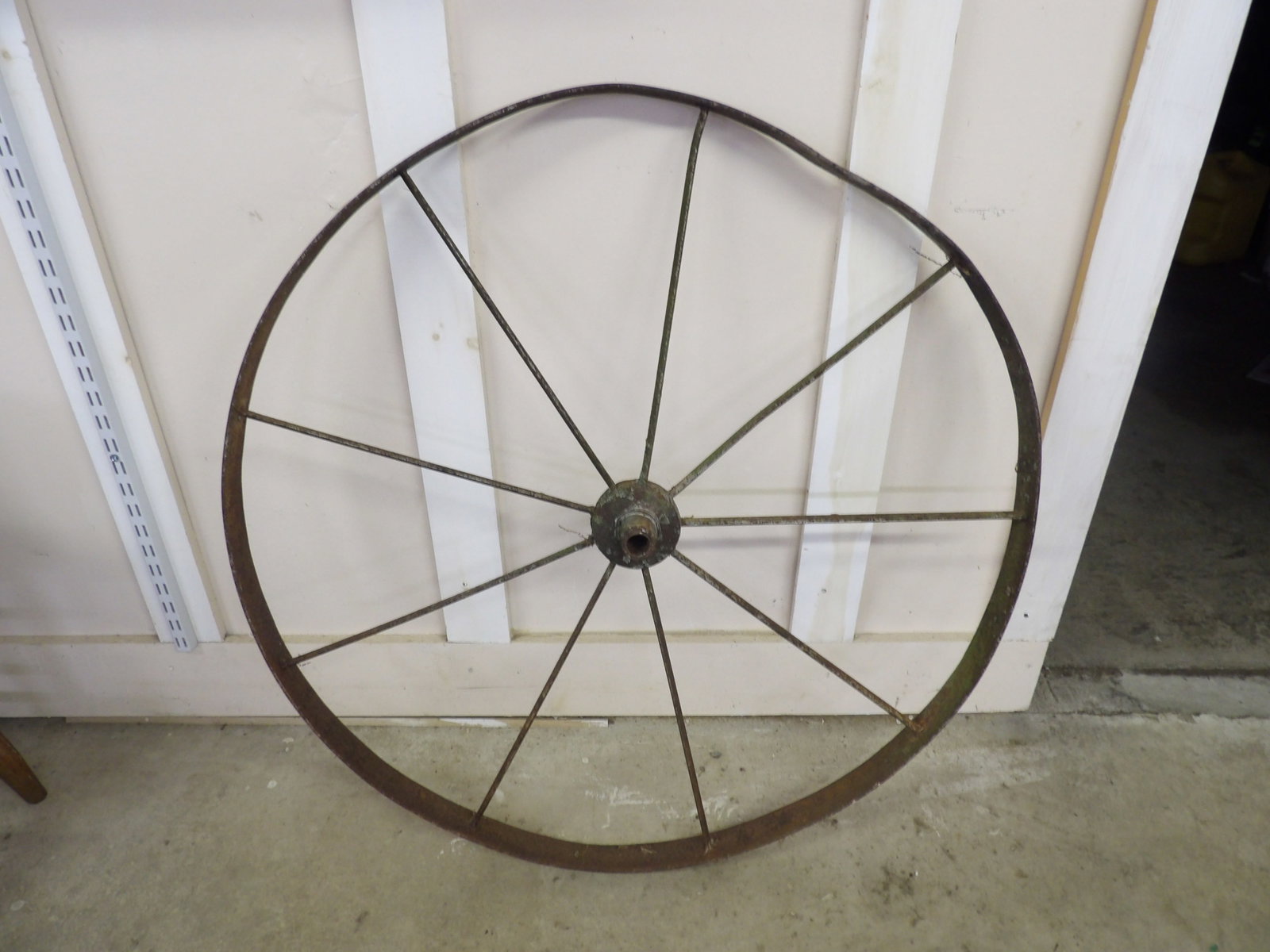 Iron Wagon Wheel: This antique iron wagon wheel features a central hub and eight spokes, weathered with a rustic patina. Has a minor dent that could be straightened out. Measures approx 36". NO SHIPPING FOR THIS ITEM