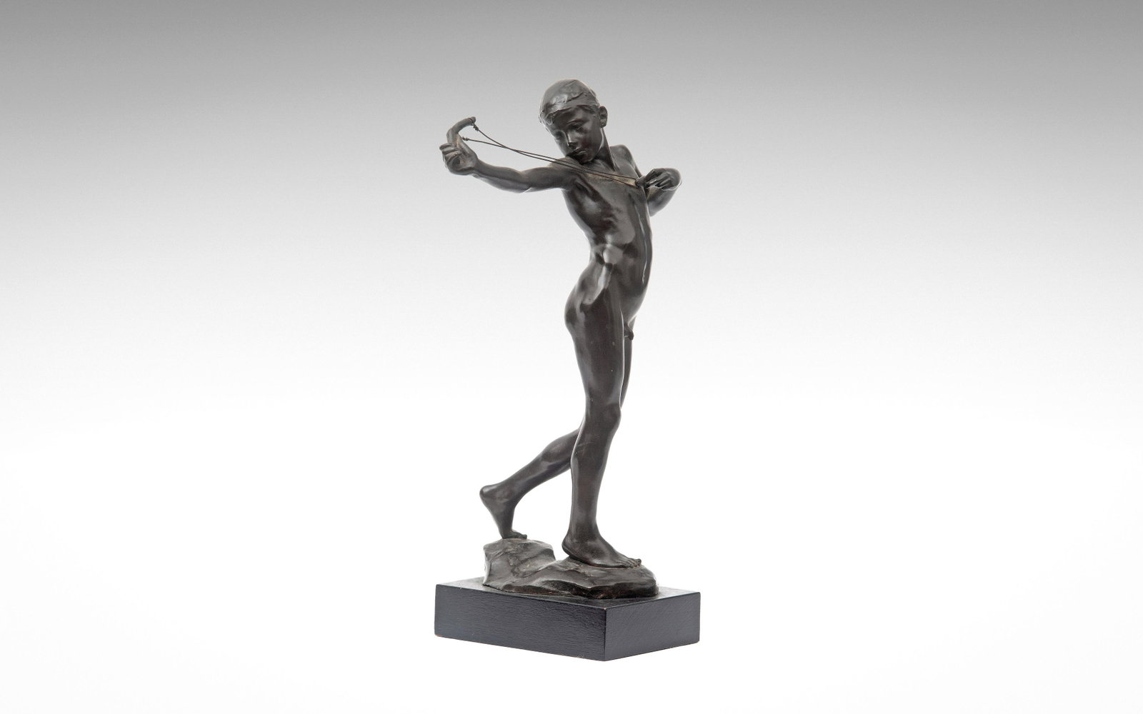 SIR WILLIAM REID DICK R.A. (BRITISH, 1879-1961): A RARE: depicting a nude boy aiming his catapult, on a naturalistic base, dark brown patination, signed 'W. Reid Dick', later mounted on an ebonised base, the bronze 36.3cm high Provenance: Sir William Reid D