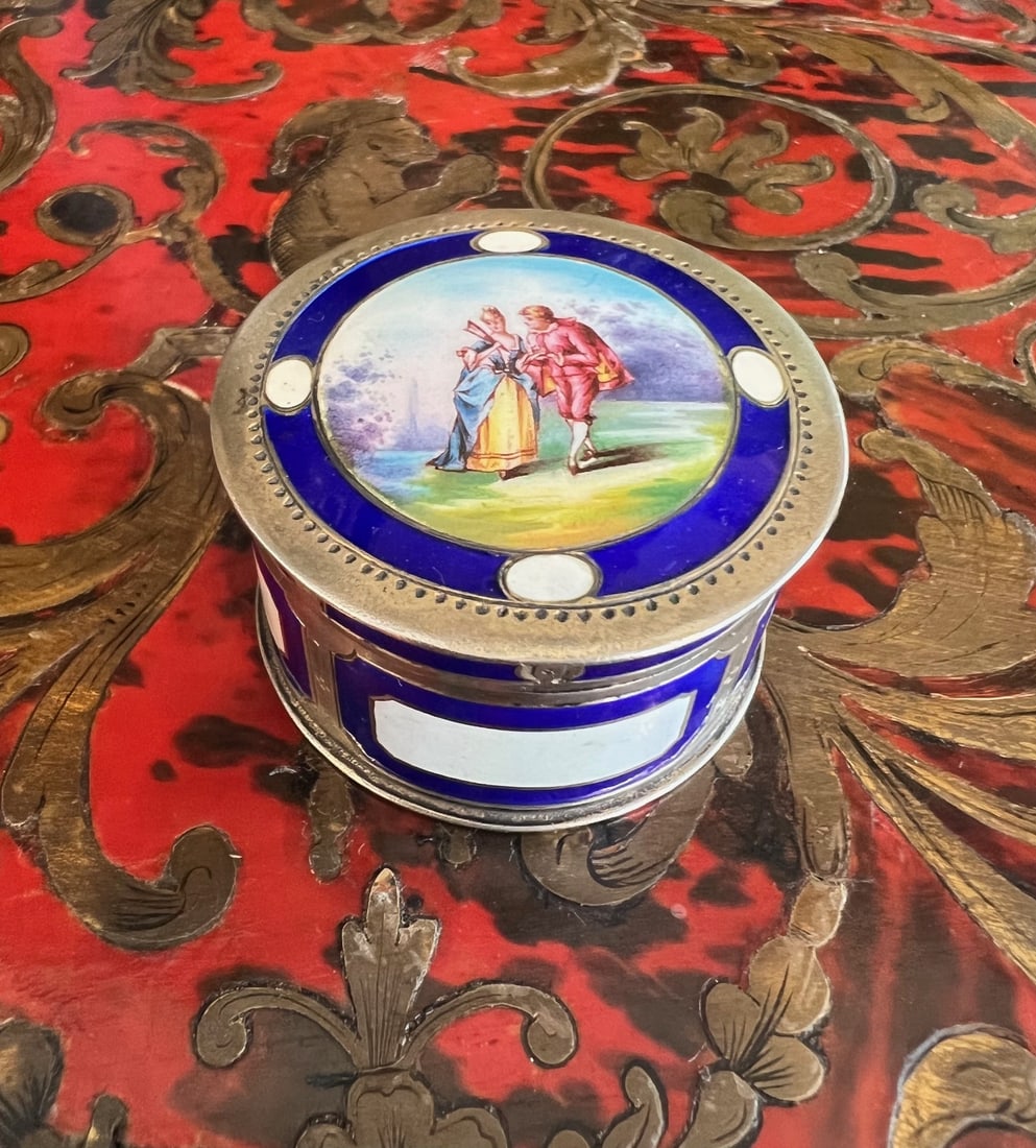 A LATE 19TH / EARLY 20TH CENTURY GERMAN ENAMEL AND SILVER PILL BOX: A LATE 19TH / EARLY 20TH CENTURY GERMAN ENAMEL AND SILVER PILL BOX A LATE 19TH / EARLY 20TH CENTURY GERMAN ENAMEL AND SILVER PILL BOX of circular form, the top with an enamelled scene of lovers, the u