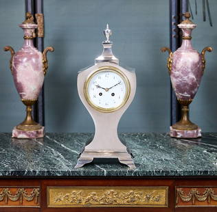 A LARGE STERLING SILVER MANTEL CLOCK CIRCA 1904 BY WILLIAM COMYNS & SONS: A LARGE STERLING SILVER MANTEL CLOCK CIRCA 1904 BY WILLIAM COMYNS &amp; SONS the antique, early 20th century Edward VII period mantel clock of shaped outline and surmounted by an urn finial, on four b