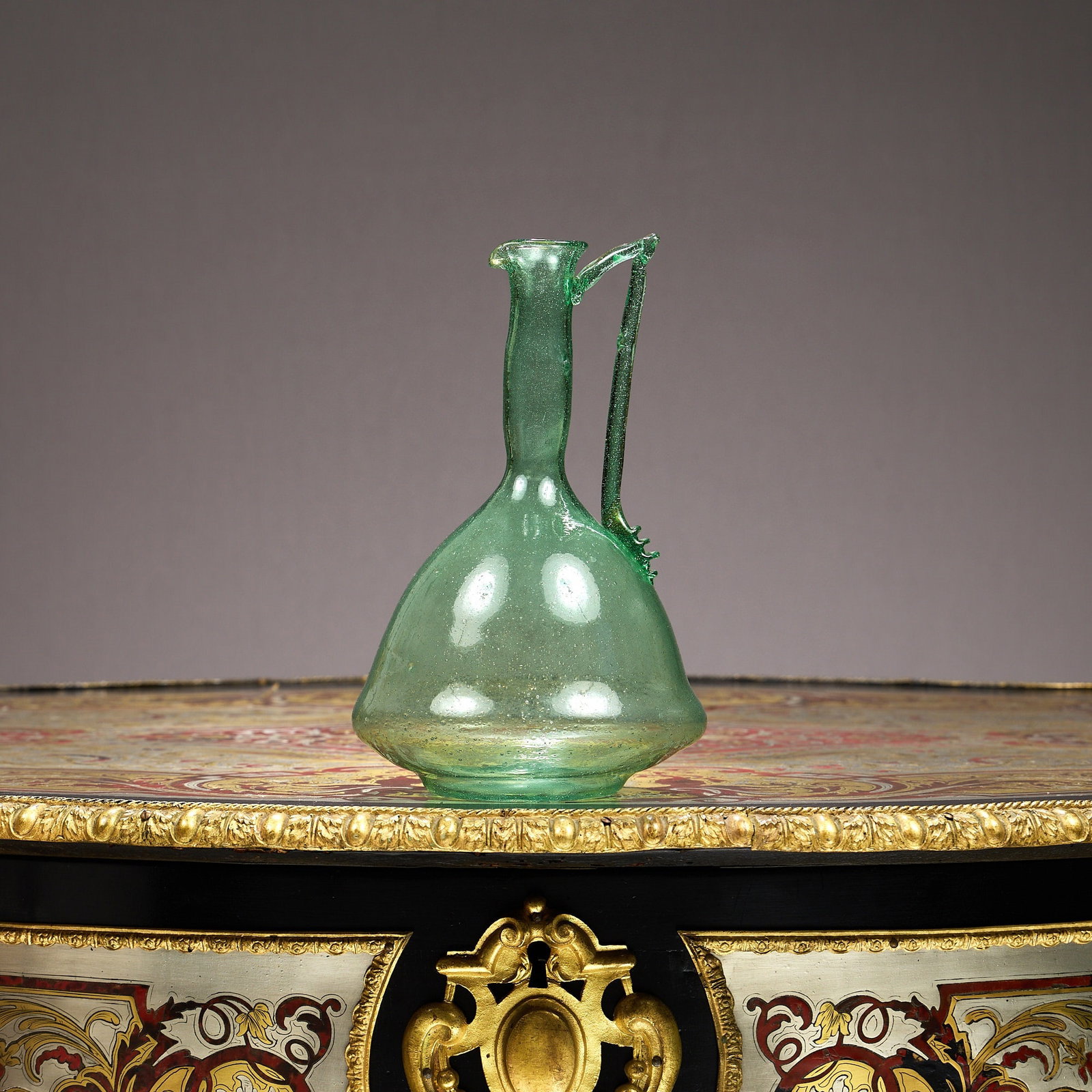 AN 18TH CENTURY STYLE GREEN GLASS SERVING BOTTLE: AN 18TH CENTURY STYLE GREEN GLASS SERVING BOTTLE the ewer or jug 'shaft and globe' style with applied handle, 25.5cm high