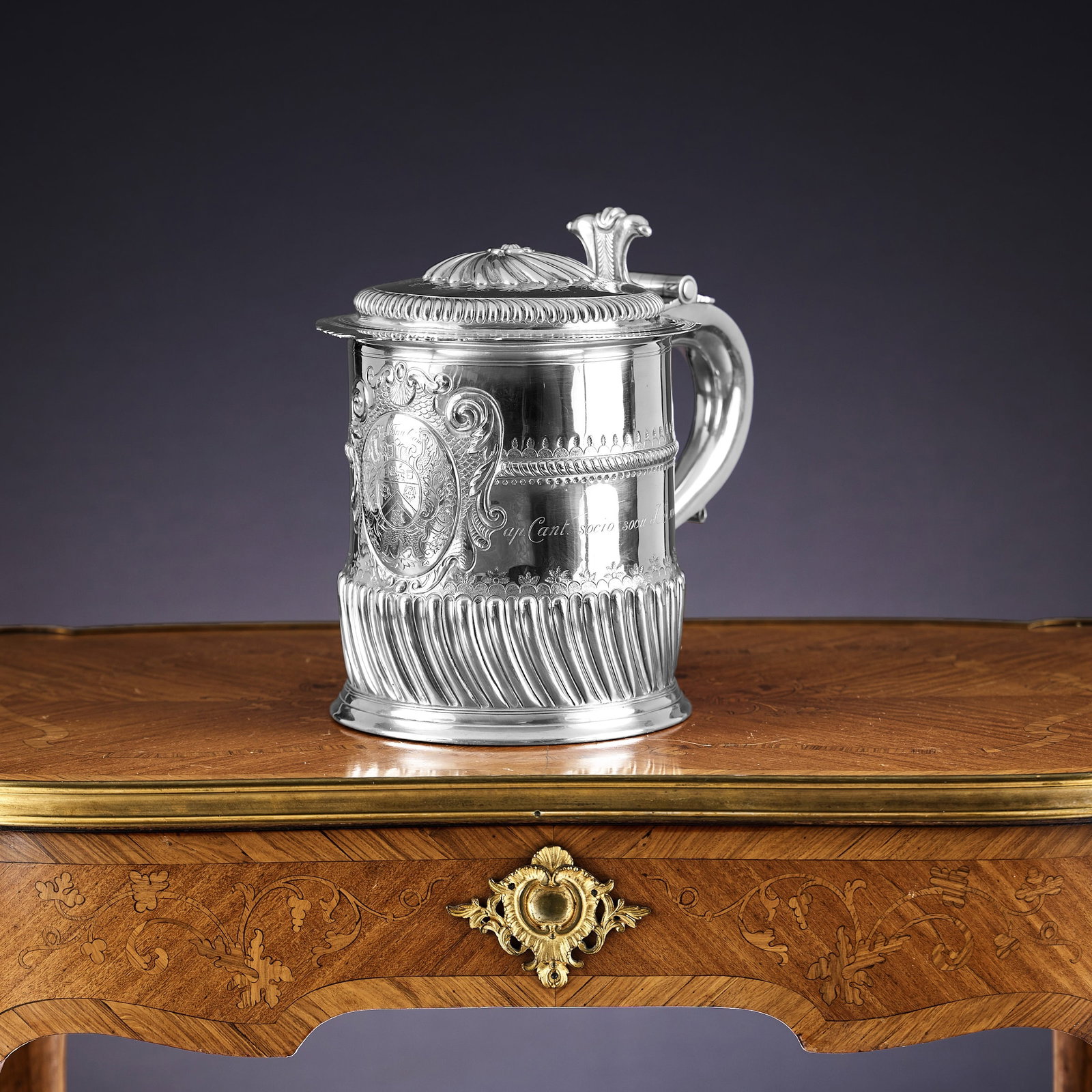 A MASSIVE BRITANNIA SILVER TANKARD BY WILLIAM COMYNS, RELATING TO TRINITY COLLEGE: A MASSIVE BRITANNIA SILVER TANKARD BY WILLIAM COMYNS, RELATING TO TRINITY COLLEGE the George V period antique early 20th century silver tankard in the 18th century style, with hinged gadrooned cover w