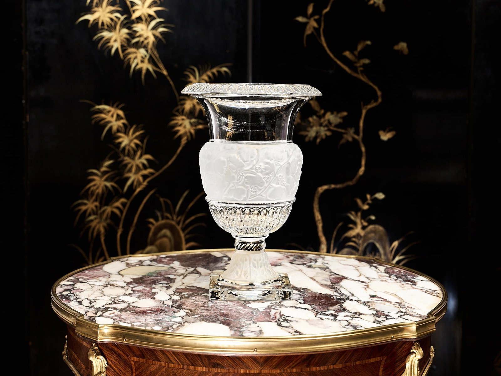A FROSTED AND GLEAR GLASS VASE IN THE STYLE OF LALIQUE: A FROSTED AND GLEAR GLASS VASE IN THE STYLE OF LALIQUE the baluster vaes with everted rim with egg and dart border, the central section of the body with frosted relief decoration of grapes and vines,