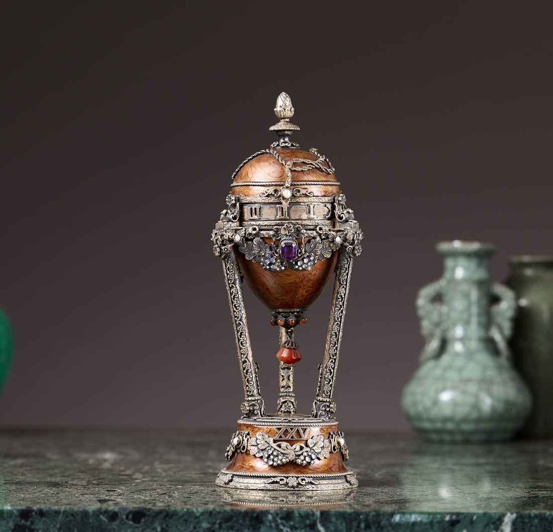 A SILVER, ENAMEL AND JEWELLED MUSICAL PENDULE A CERCLES TOURNANTS CLOCK: A SILVER, ENAMEL AND JEWELLED MUSICAL PENDULE A CERCLES TOURNANTS CLOCK in the form of a pendule a cercles tournants, the egg shaped case decorated in the Russian Faberge style in the manner of an Imp