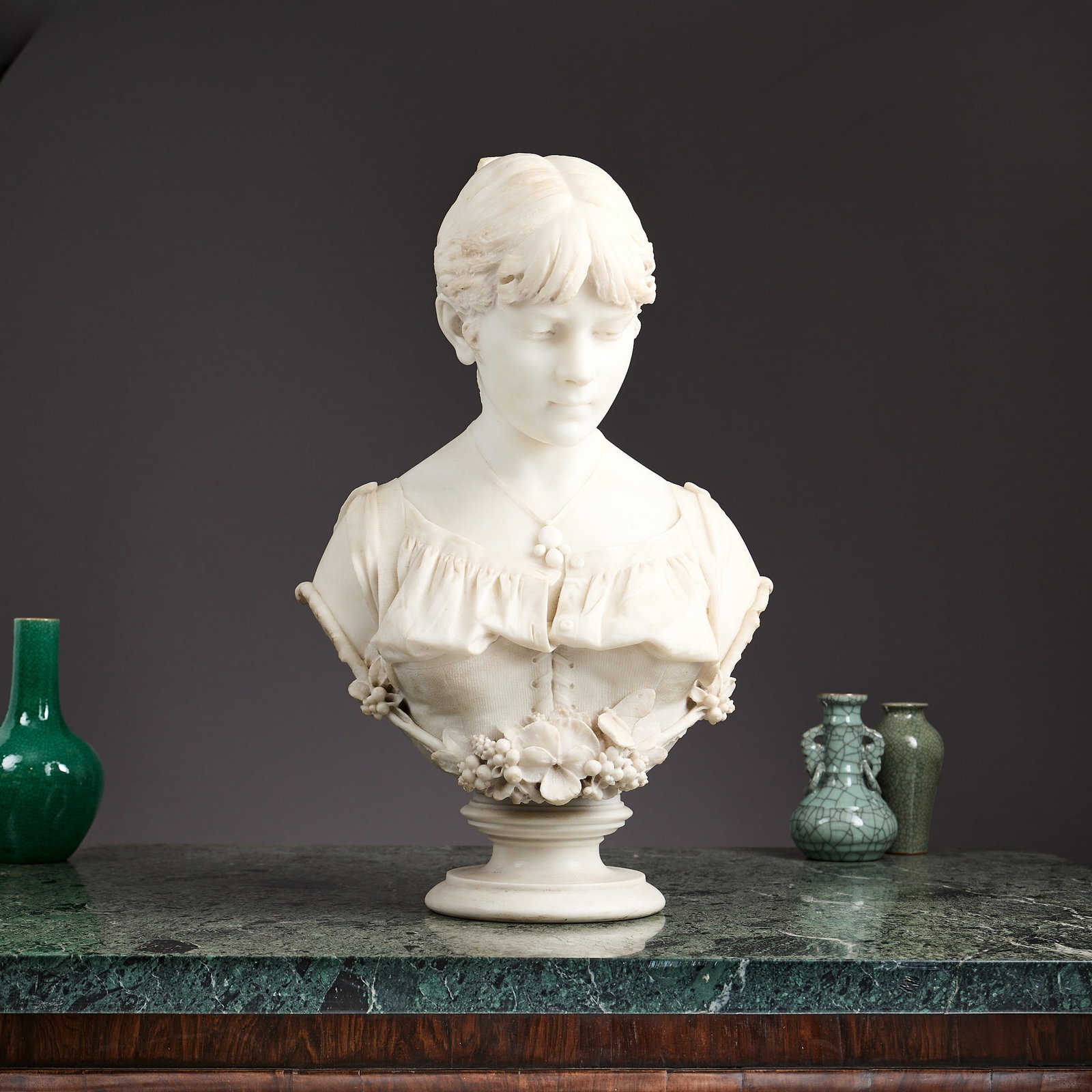 ANTONIO CAMBI (1847-1925): A 19TH CENTURY MARBLE BUST OF A GIRL: ANTONIO CAMBI (1847-1925): A 19TH CENTURY MARBLE BUST OF A GIRL the life-size Italian carrara marble bust depicting a young peasant girl adorned with flowers, on a waisted, cylindrical socle, the reve