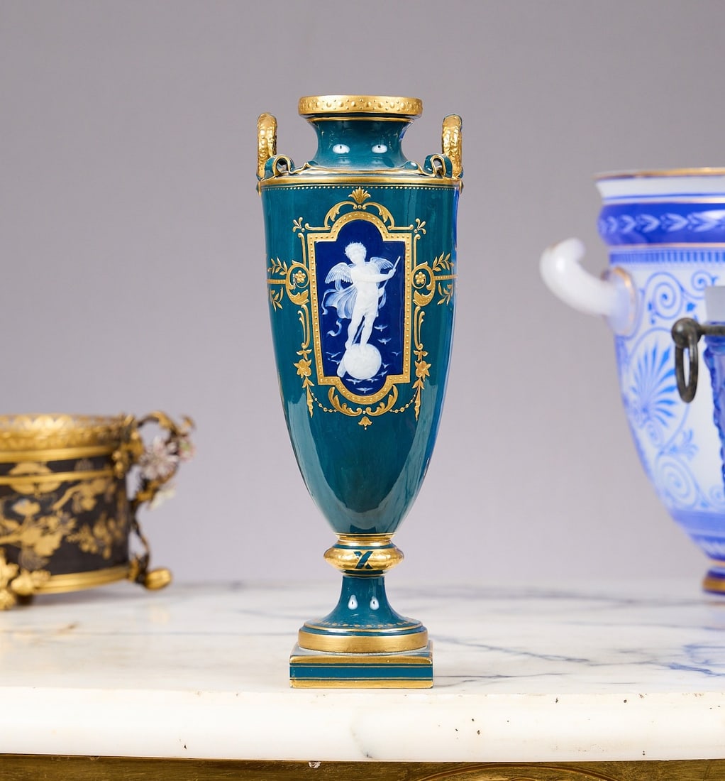 A FINE MINTON PATE-SUR-PATE PORCELAIN VASE BY ALBION BIRKS, C. 1909: A FINE MINTON PATE-SUR-PATE PORCELAIN VASE BY ALBION BIRKS, C. 1909 the pate sur pate vase of slender tapering shape, with a pair of handles formed as ribbon tied wreaths, on a spreading socle and squ