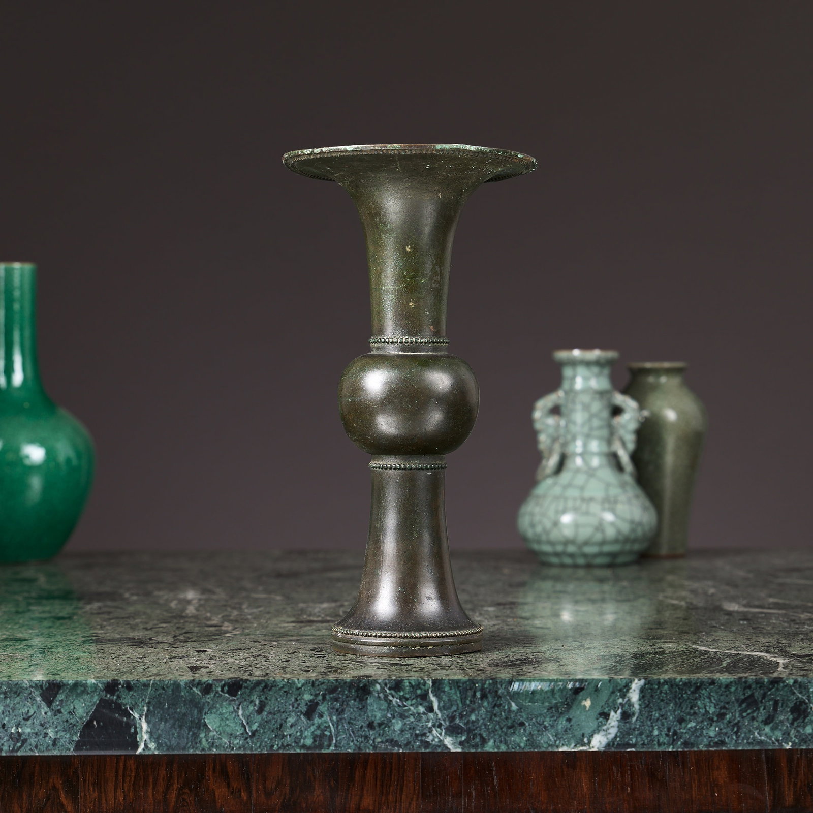 A CHINESE BRONZE TRUMPET VASE: A CHINESE BRONZE TRUMPET VASE Qing dynasty, brown patinated, with everted rim and circular beaded foot, unmarked, 27cm high