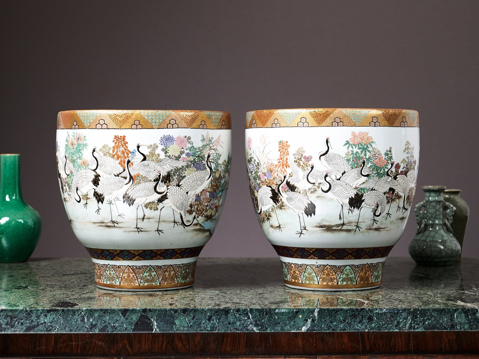 A LARGE PAIR OF JAPANESE MEIJI PERIOD KUTANI PORCELAIN JARDINIERES: A LARGE PAIR OF JAPANESE MEIJI PERIOD KUTANI PORCELAIN JARDINIERES late 19th / early 20th century, decorated with numerous cranes amongst flowers on a white ground, with gilt decorative borders to the