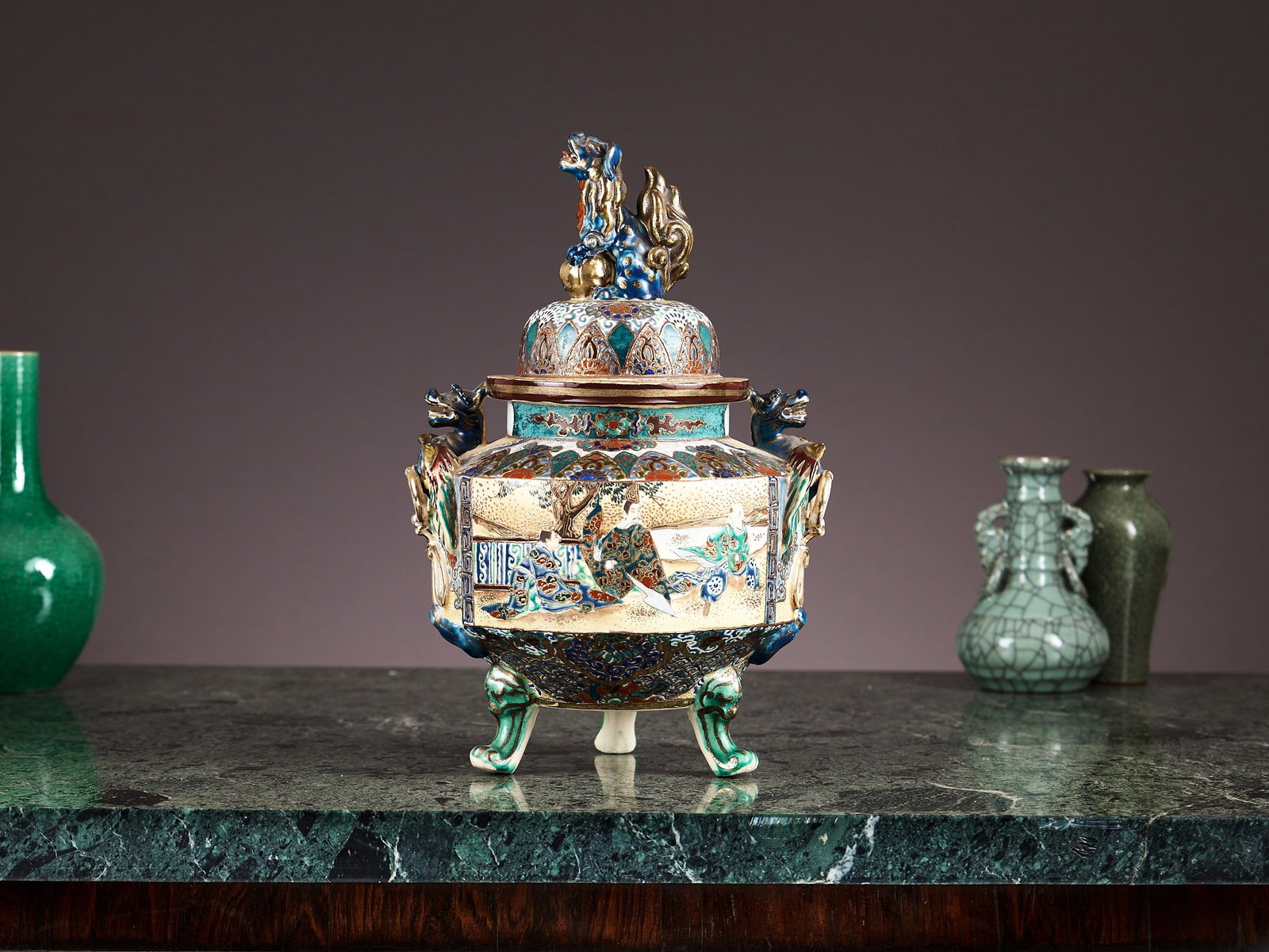 A JAPANESE MEIJI PERIOD SATSUMA WARE KORO: A JAPANESE MEIJI PERIOD SATSUMA WARE KORO late 19th / early 20th century, the glazed ceramic incense burner or vase and cover with a domed lid surmounted by Foo dog finial, of cylindrical, tripod form