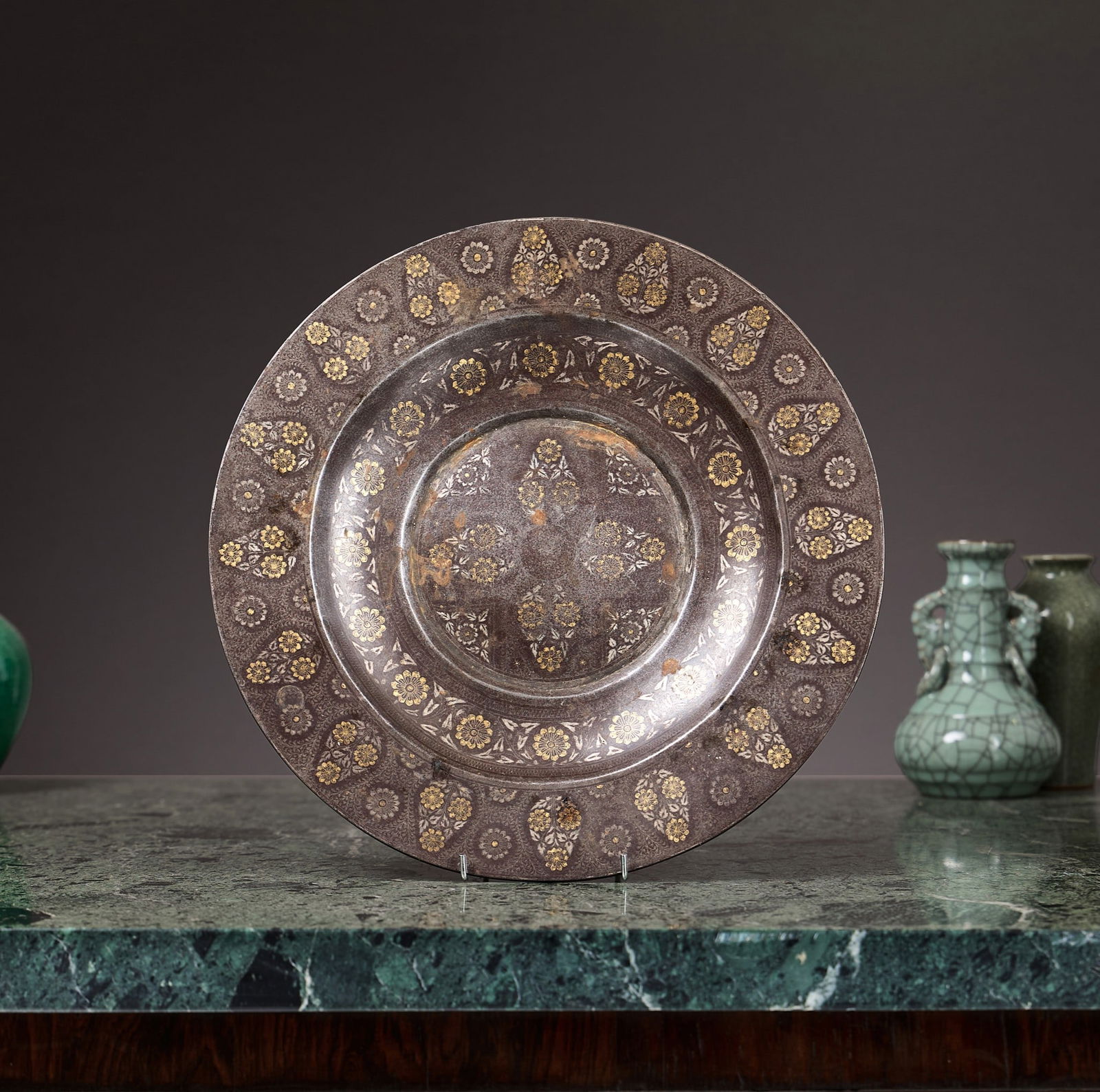 A GOLD AND SILVER INLAID KOFTGARI DISH, INDIAN, 19TH CENTURY: A GOLD AND SILVER INLAID KOFTGARI DISH, INDIAN, 19TH CENTURY the dish or tray or circular form with recessed centre, decorated throughout with gold and silver flowerheads and floral tendrils, 34.5cm d