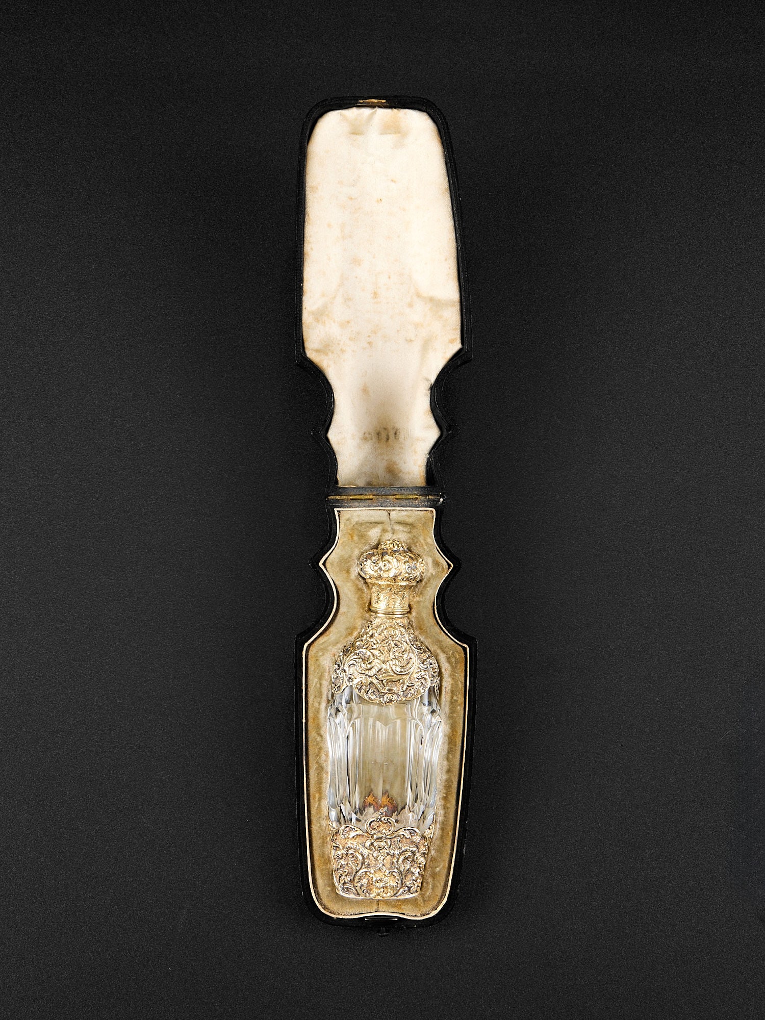 A FINE SILVER GILT AND GLASS SCENT BOTTLE ATTRIBUTED TO MOREL C. 1900: A FINE SILVER GILT AND GLASS SCENT BOTTLE ATTRIBUTED TO MOREL C. 1900 the late 19th century perfume bottle richly decorated with Rococo motifs, with hinged cover enclosing glass stopper, in original l