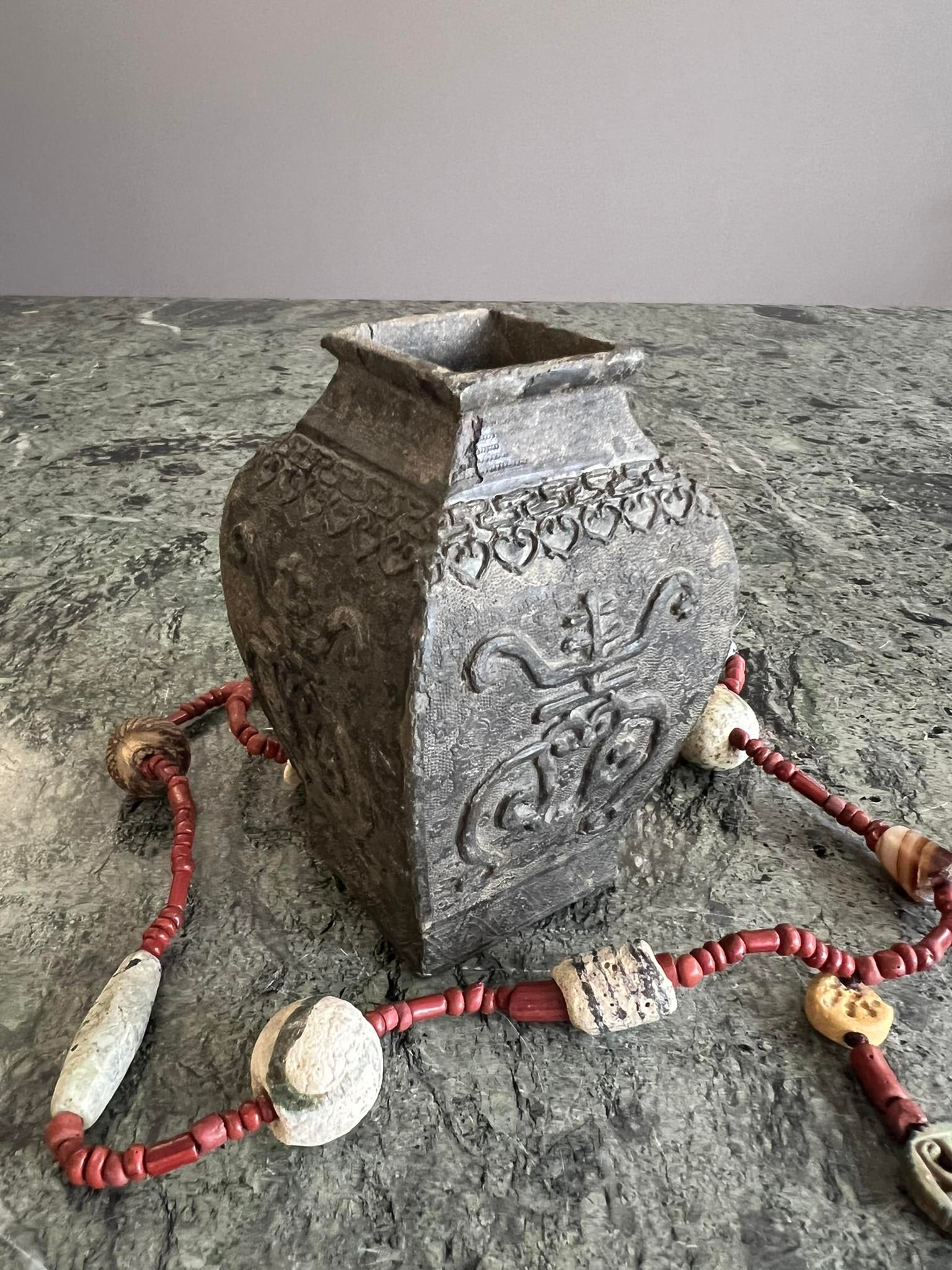 A CHINESE ARCHAIC STYLE BRONZE VASE TOGETHER WITH A NECKLACE: A CHINESE ARCHAIC STYLE BRONZE VASE TOGETHER WITH A NECKLACE the small vase with relief decoration, on a square foot with baluster shaped sides, together with a Middle Eastern hardstone and glass neck