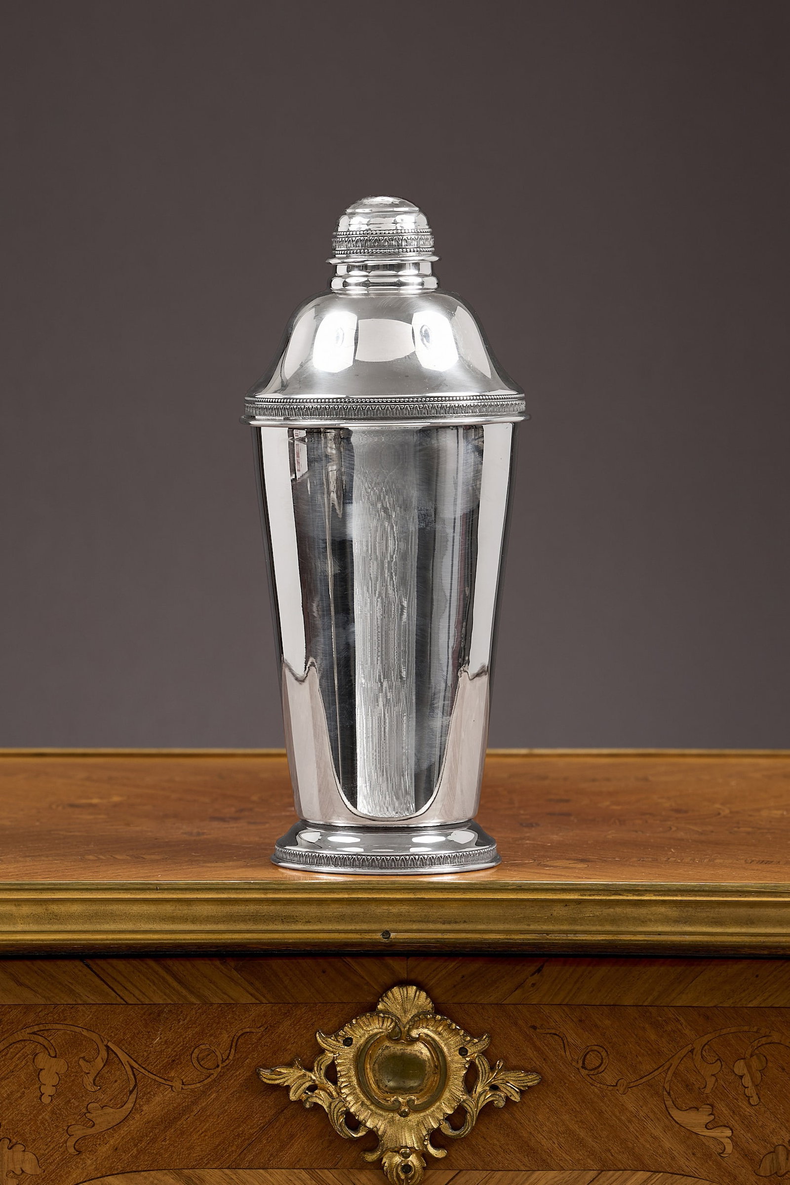 AN ITALIAN SILVER COCKTAIL SHAKER: AN ITALIAN SILVER COCKTAIL SHAKER the tapering body raised on a circular foot, the foot, cover and lid all with decorative foliate border, marked 800 and with Italian silver marks to underside, 317g (