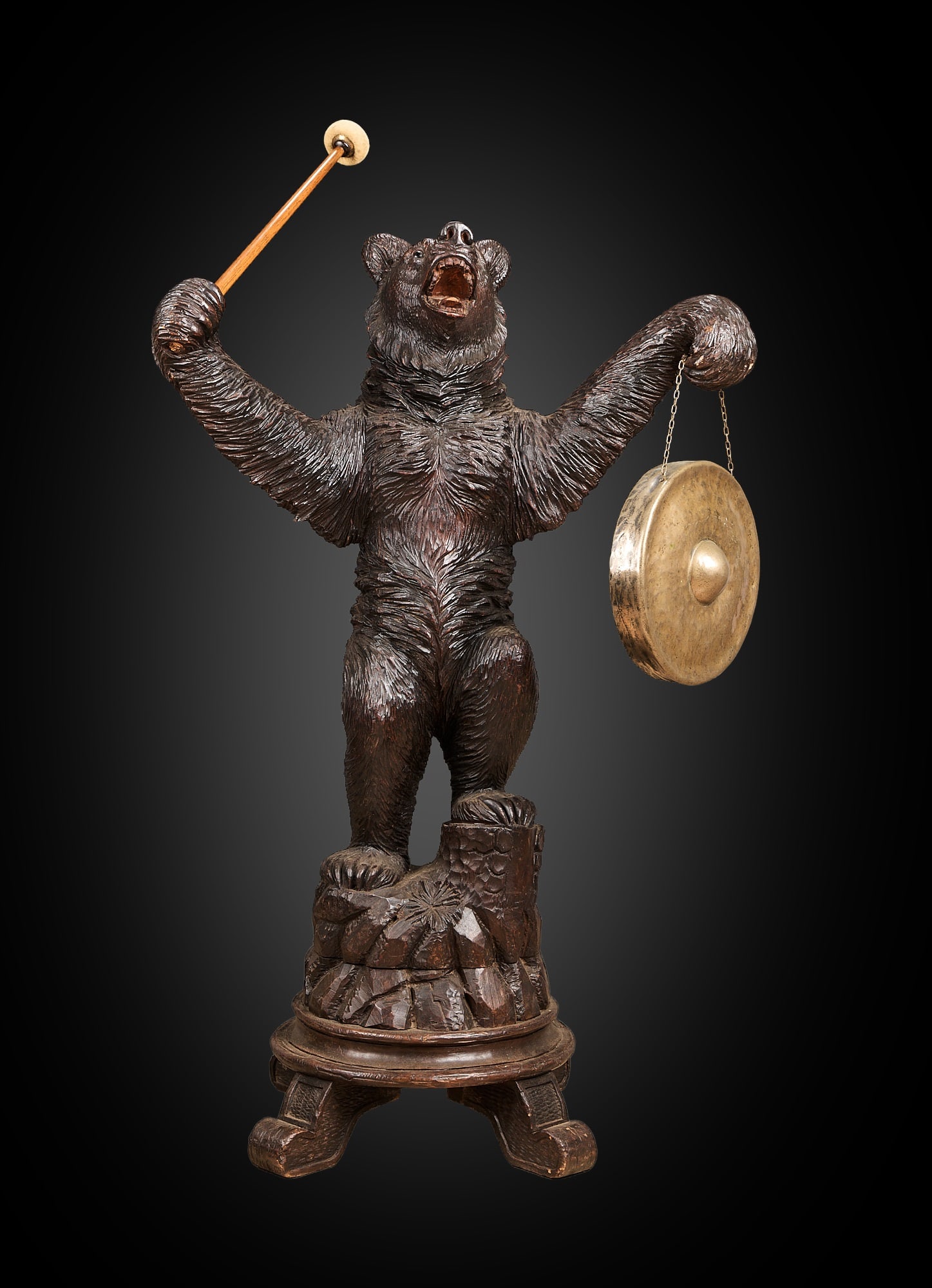 A LARGE 19TH CENTURY BLACK FOREST CARVED BEAR GONG: A LARGE 19TH CENTURY BLACK FOREST CARVED BEAR GONG the carved lindenwood standing bear with open mouth revealing tongue and teeth, with glass eyes, raised on naturalistic base over four scroll feet, h