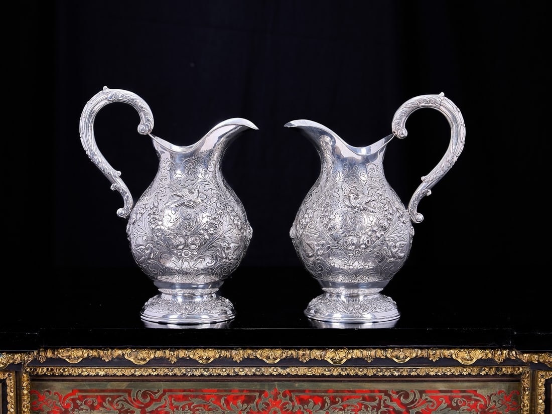 A FINE PAIR OF ANTQUE GERMAN SILVER CLARET JUGS: A FINE PAIR OF ANTQUE GERMAN SILVER CLARET JUGS the wine jugs in the 18th century Rococo style, each with an acanthus wrapped, scrolling handle and raised on circular feet, decorated profusely with ho
