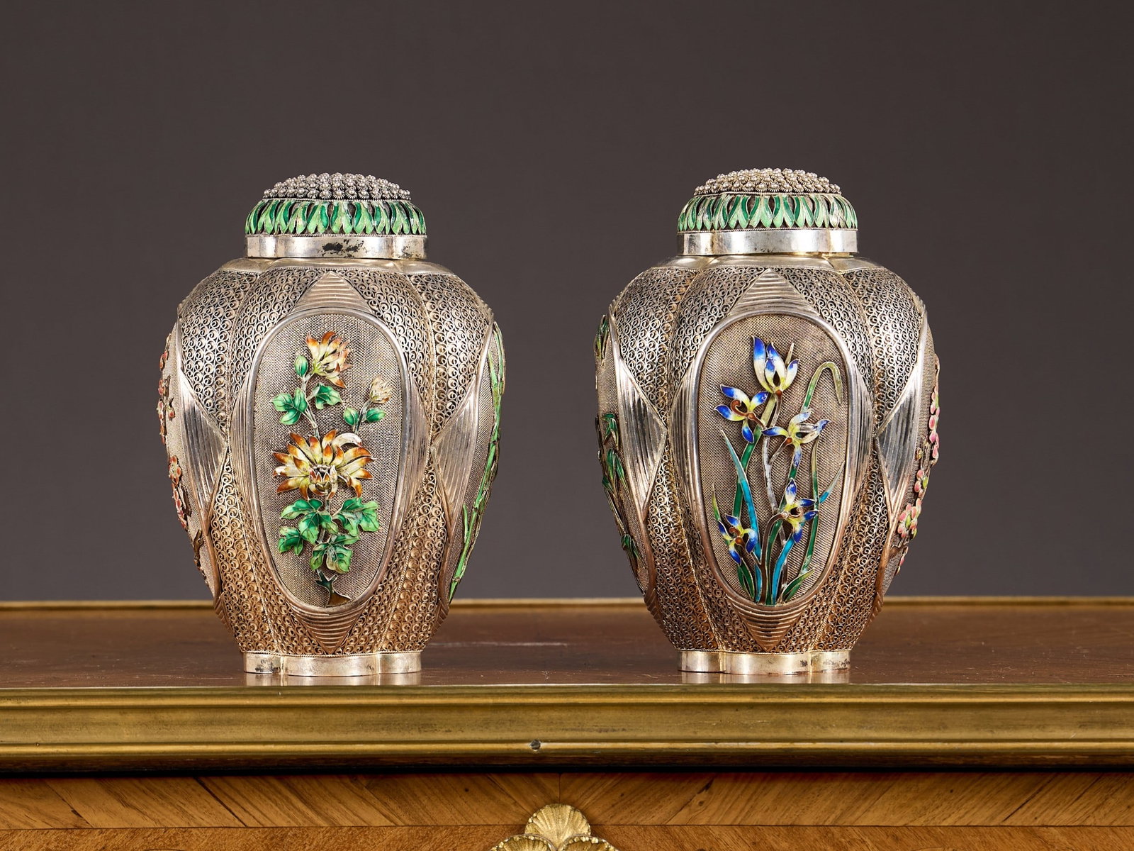 A RARE PAIR OF CHINESE SILVER AND CLOISONNE ENAMEL TEA CADDIES: A RARE PAIR OF CHINESE SILVER AND CLOISONNE ENAMEL TEA CADDIES 20th century, Chinese export, the four lobed, tapering bodies decorated with four oval panels of applied cloisonne enamelled flowers incl