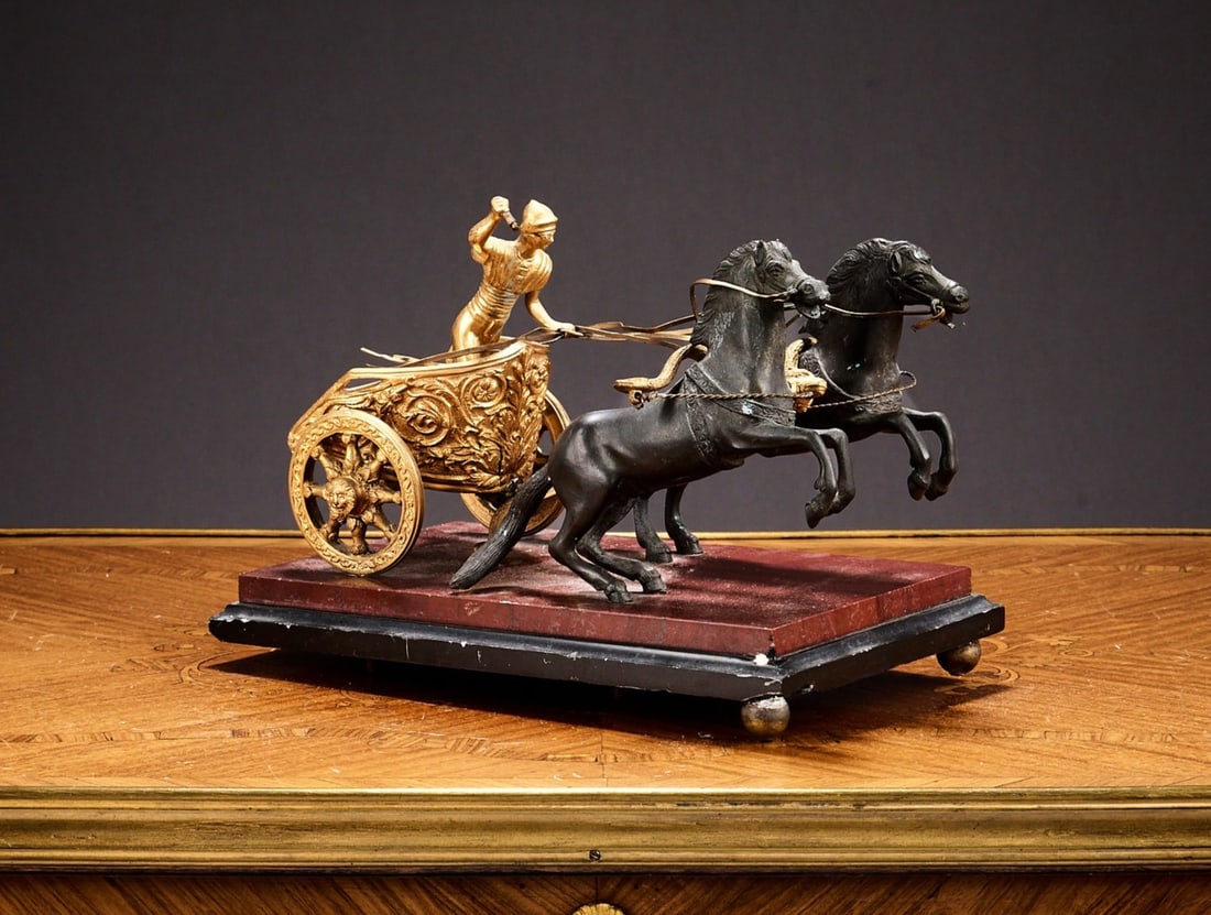 A 19TH CENTURY GRAND TOUR MODEL OF A CHARIOT AND HORSES: A 19TH CENTURY GRAND TOUR MODEL OF A CHARIOT AND HORSES the Italian gilt and patinated bronze model of a Roman charioteer and a pair of horses on a rouge griotte marble plinth, 21cm wide x 13cm high