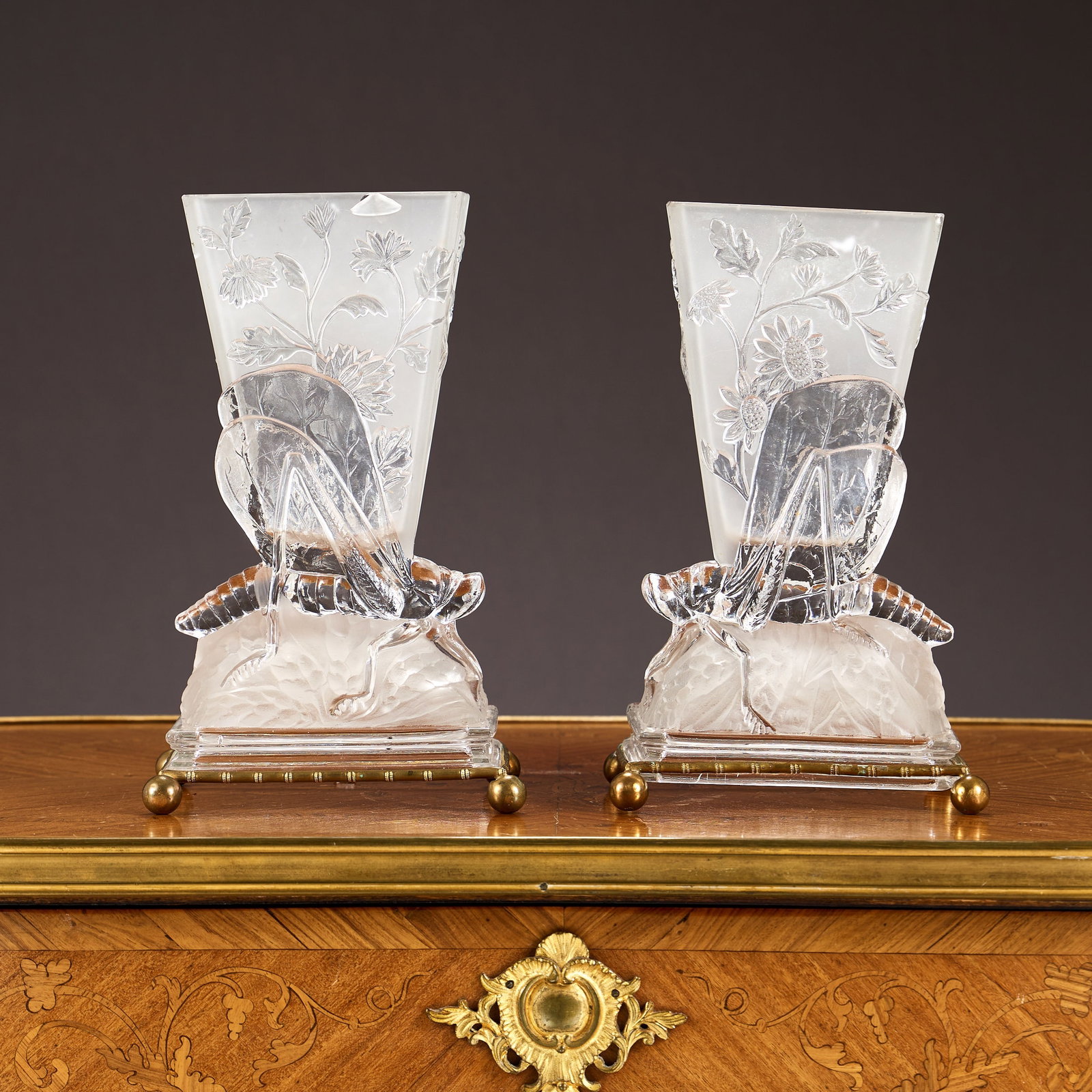 BACCARAT: A RARE PAIR OF GRASSHOPPER VASES: BACCARAT: A RARE PAIR OF GRASSHOPPER VASES the clear and frosted crystal glass vases each with a tapering vase with sunflower decoration atop the back of a grasshopper, over rectangular bases and rais