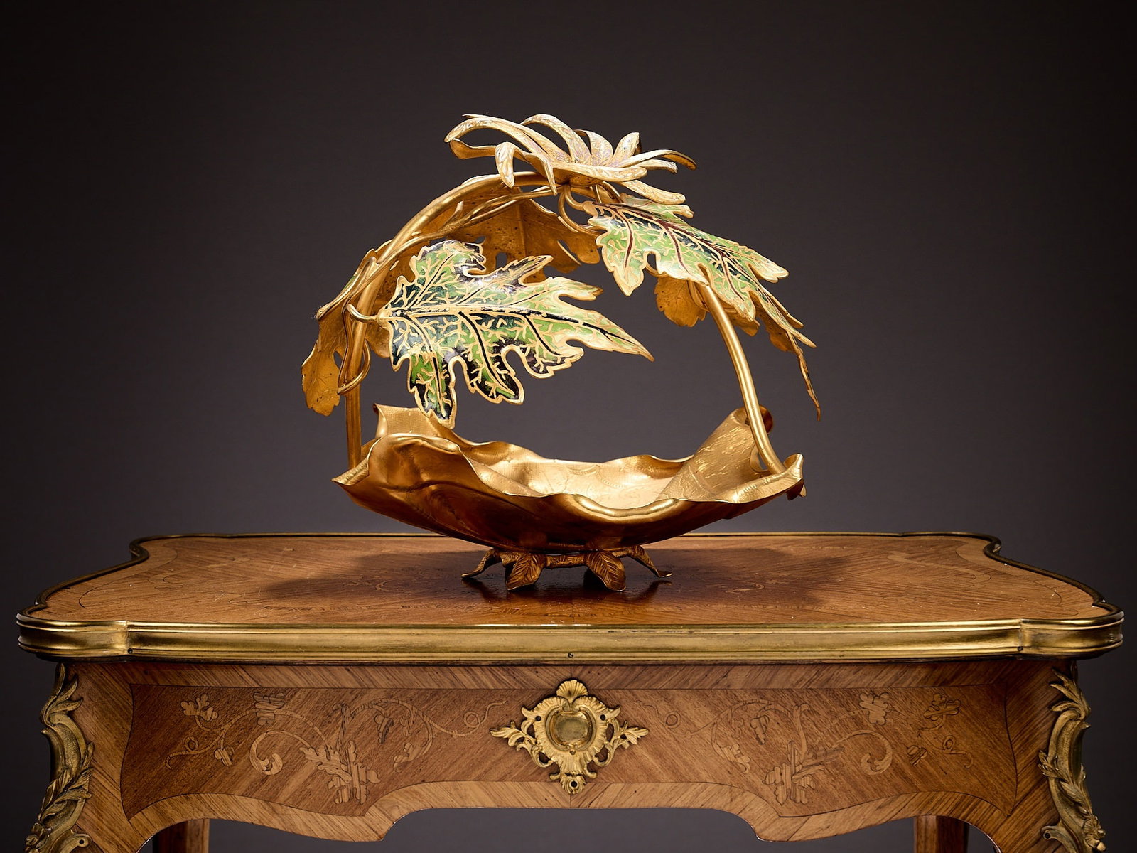 A LARGE FRENCH GILT METAL AND CHAMPLEVE ENAMEL CENTREPIECE BOWL: A LARGE FRENCH GILT METAL AND CHAMPLEVE ENAMEL CENTREPIECE BOWL 20th century, formed as a chased leaf shaped bowl with scrolling acorn leaves and a flower over, with enamelled decoration, 41cm wide x 