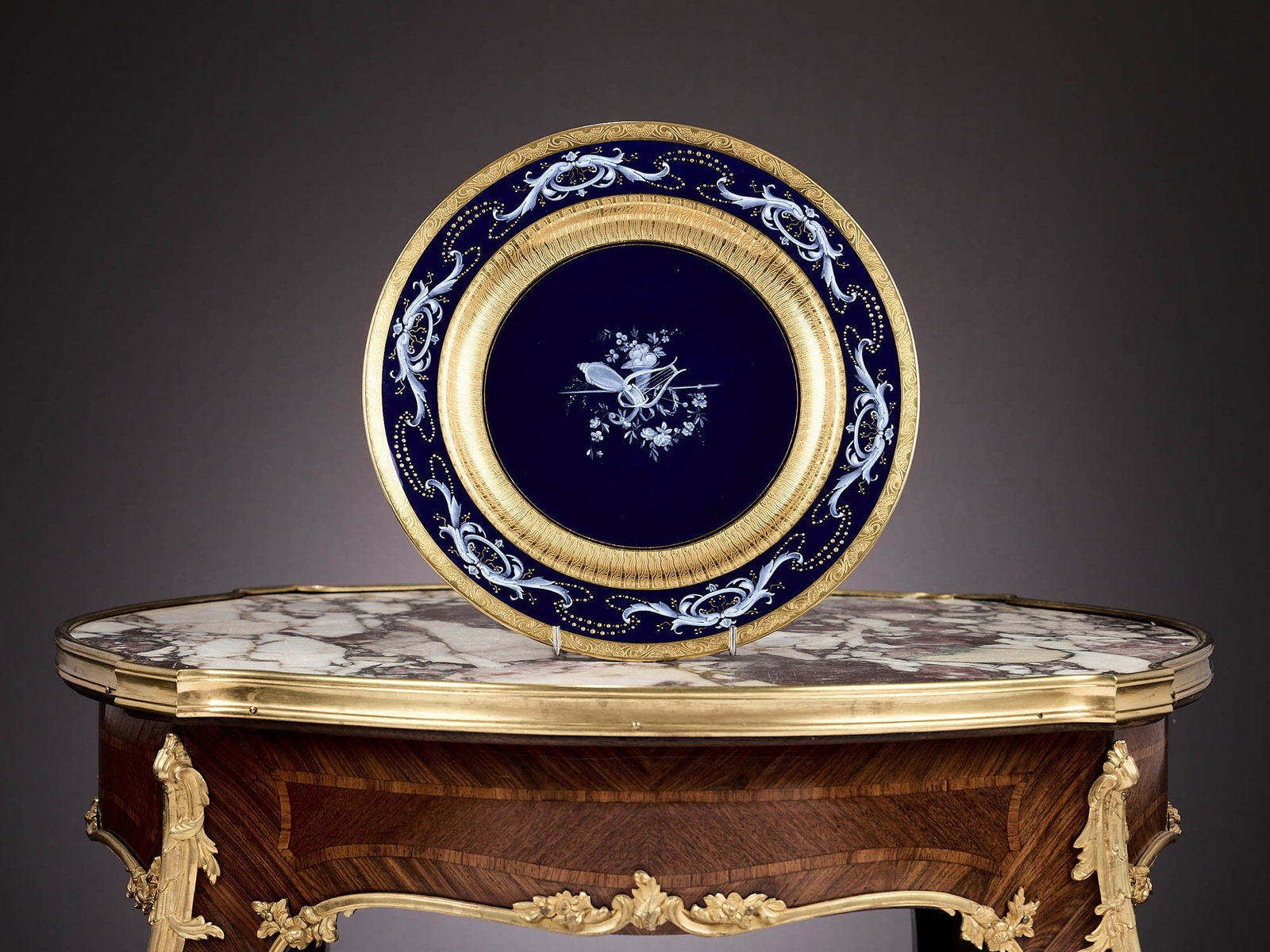 A MINTON PATE-SUR-PATE PORCELAIN CABINET PLATE: A MINTON PATE-SUR-PATE PORCELAIN CABINET PLATE the cobalt blue body with pate sur pate decoration in the Renaissance style of scrolling acanthus leaves to the rim and trophy with lyre and cornucopia t