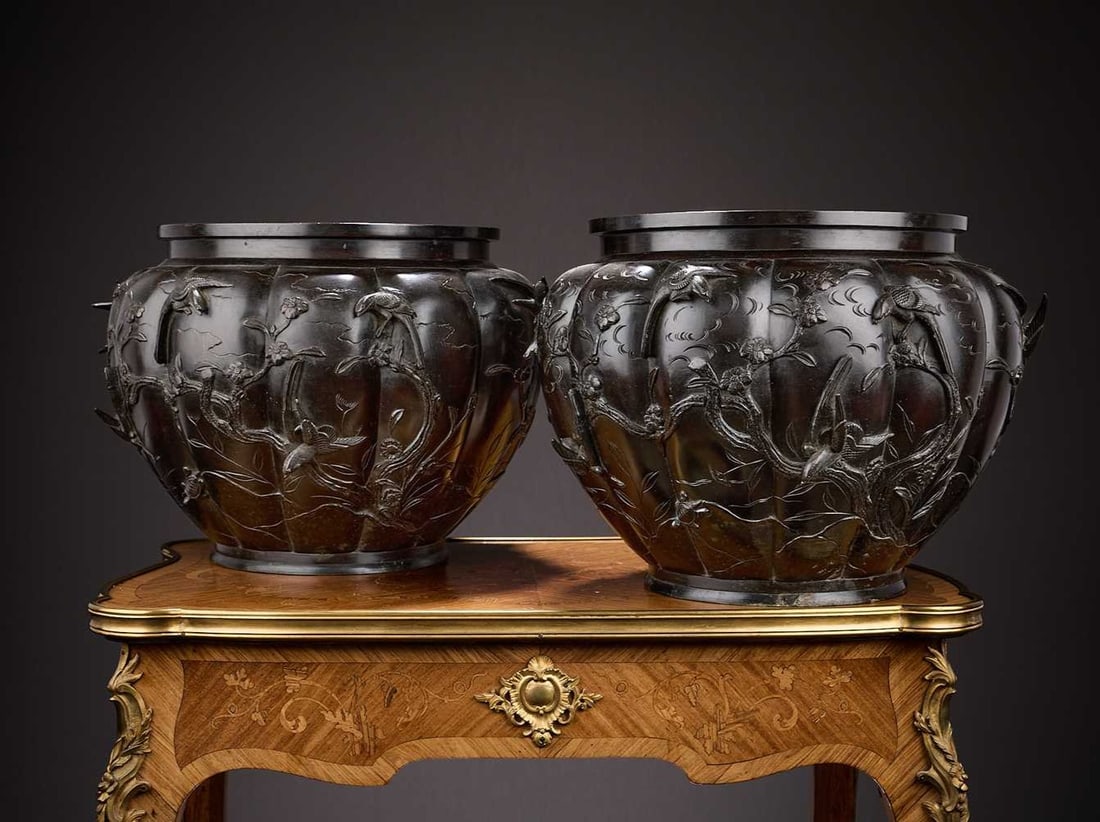A LARGE PAIR OF JAPANESE MEIJI PERIOD BRONZE JARDINIERES: A LARGE PAIR OF JAPANESE MEIJI PERIOD BRONZE JARDINIERES of lobed form, with applied birds amongst reliefs of flowers, on circular feet, marked to undersides, 39cm wide x 27cm high (2)