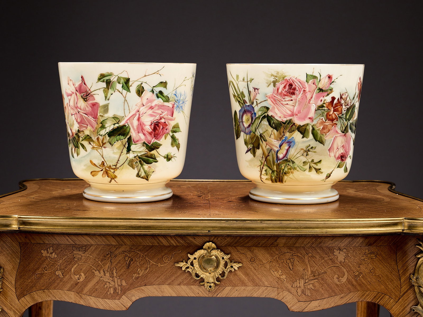 A PAIR OF EARLY 20TH CENTURY OPALINE GLASS JARDINIERES ATTRIBUTED TO BACCARAT: A PAIR OF EARLY 20TH CENTURY OPALINE GLASS JARDINIERES ATTRIBUTED TO BACCARAT painted with roses and other flowers, the vases of slightly tapering form on circular bases, 20cm high x 20.5cm wide (2)