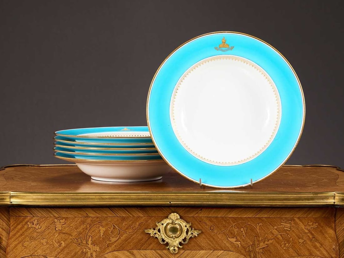 A SET OF SIX MINTON PORCELAIN CRESTED DINNER PLATES: A SET OF SIX MINTON PORCELAIN CRESTED DINNER PLATES turquoise on a white ground, with gilt decoration and gilt crest to each with armorial motto 'omne bonum superne' marked to underside 'MANUFACTURED 
