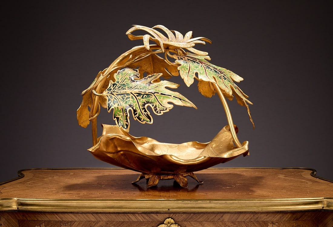A LARGE FRENCH GILT METAL AND CHAMPLEVE ENAMEL CENTREPIECE BOWL: A LARGE FRENCH GILT METAL AND CHAMPLEVE ENAMEL CENTREPIECE BOWL 20th century, formed as a chased leaf shaped bowl with scrolling acorn leaves and a flower over, with enamelled decoration, 41cm wide x 