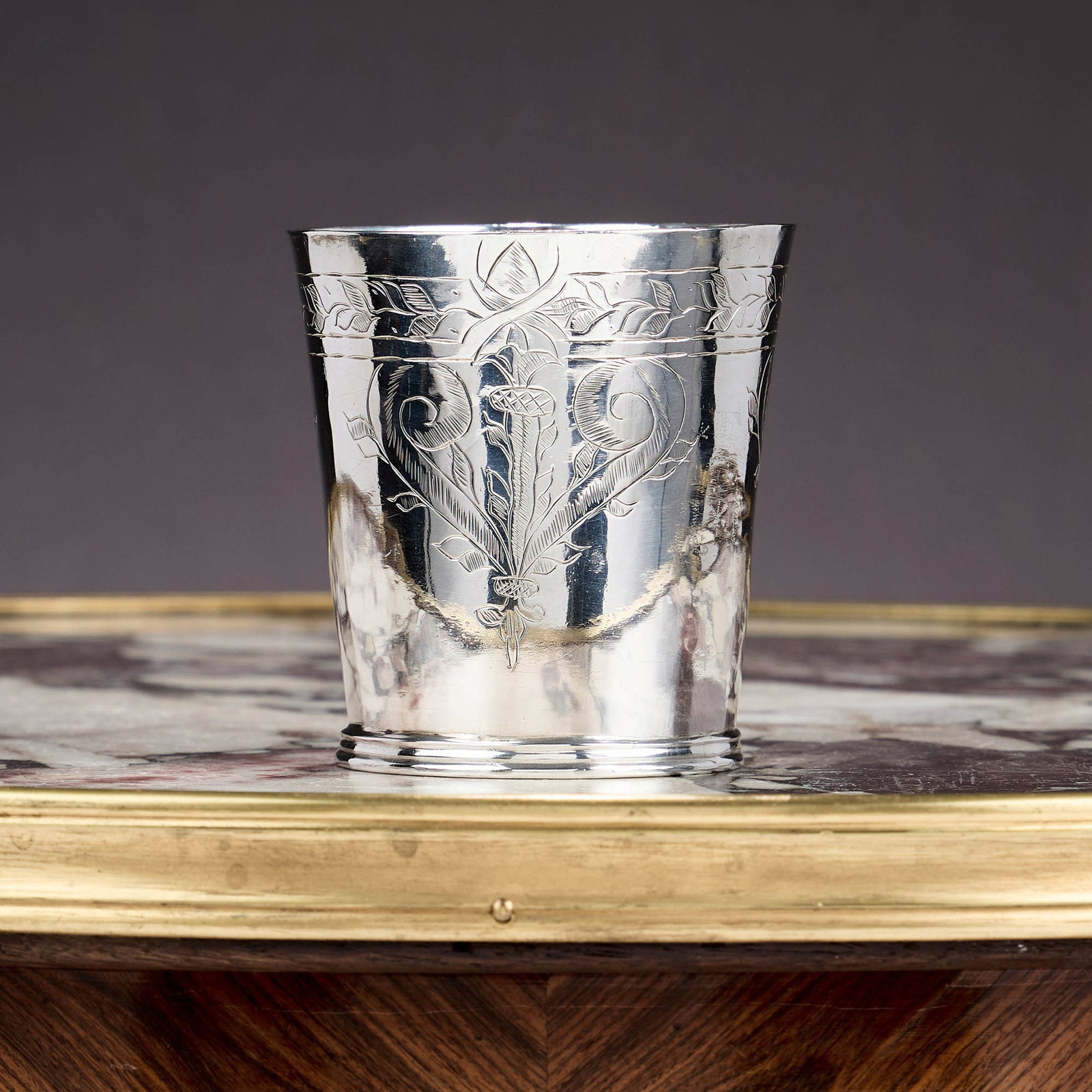 AN EXCEPTIONAL CHARLES II STERLING SILVER BEAKER C. 1662, JOHN CRUTTALL: AN EXCEPTIONAL CHARLES II STERLING SILVER BEAKER C. 1662, JOHN CRUTTALL the 17th century silver cup with engraved motif of a thrysus flanked by a pair of scrolls repeated three times to the gently tap