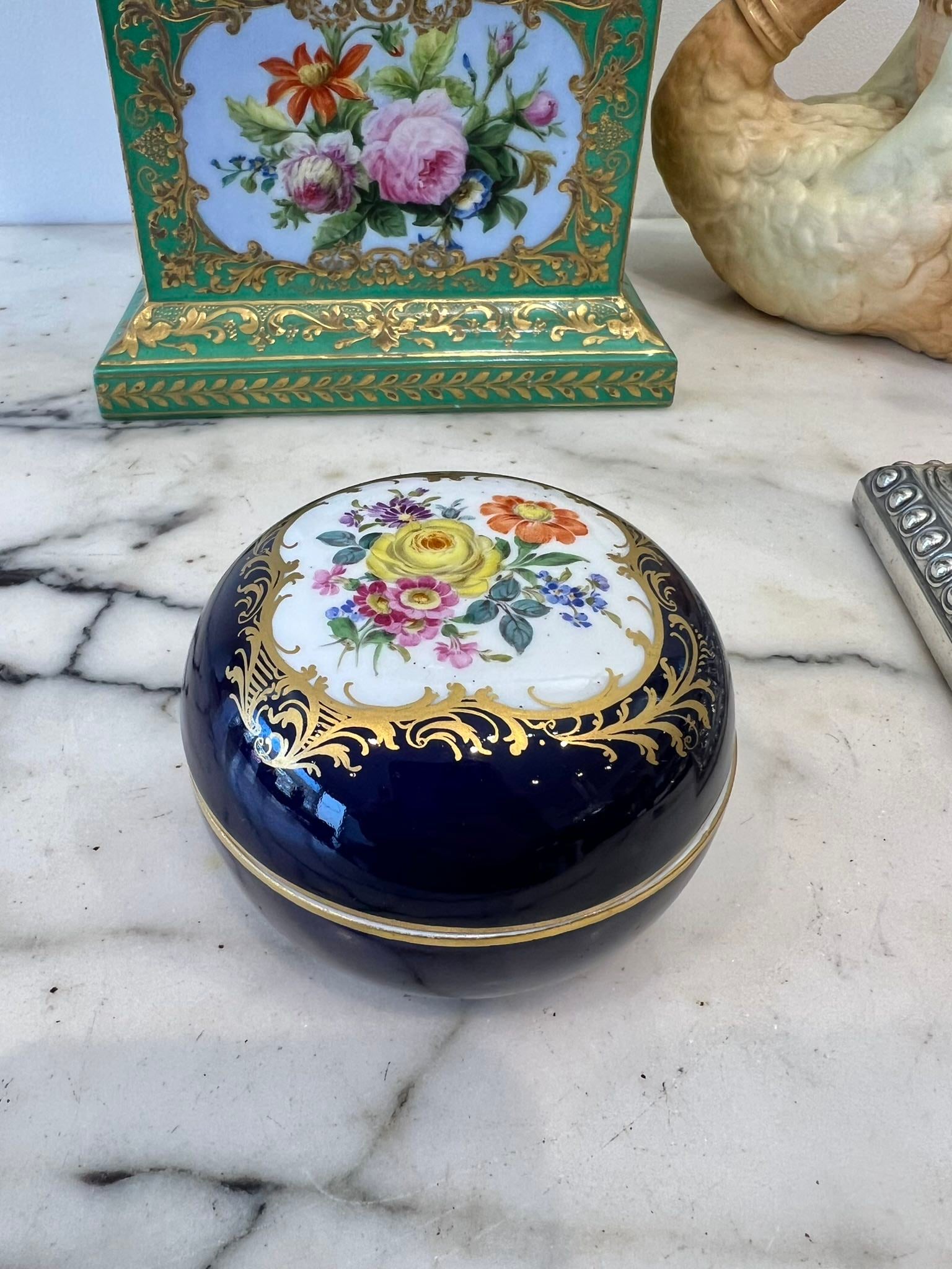 MEISSEN: A 19TH CENTURY PORCELAIN BOX: MEISSEN: A 19TH CENTURY PORCELAIN BOX of circular form, the cover decorated with a bouquet of flowers within a gilt border, on a cobalt blue ground, the underside with underglaze blue crossed swords m