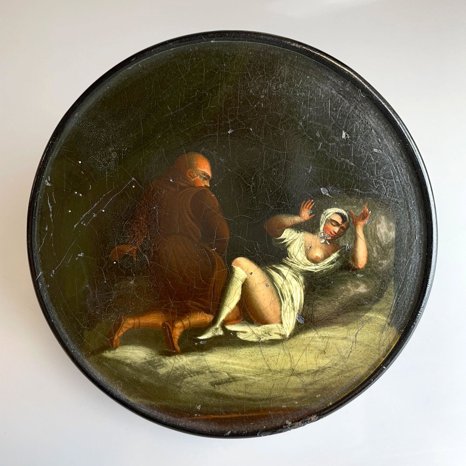Wooden casket with depiction of a sinful monk (XIX).: Diameter circa 10 cm, height circa 3.2 cm. Lid with polychrome nude depiction. Crackled, condition commensurate with age.