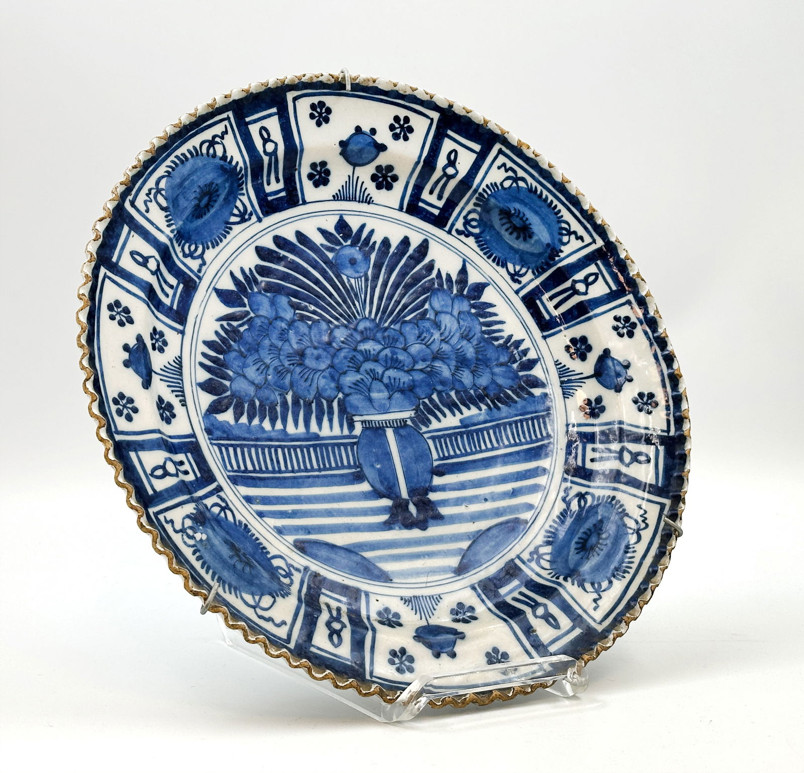 Large Delft peacock plate in Japanese style.: Circa 31 cm im Durchmesser. Fayence. Blauweiß-Malerei. Unterglasurblaue Bemalung mit Blumenstrauß im Spiegel. Felder in der Fahne mit Blumen und Symbolen. Altersbedingte Gebrauchsspuren. Farbabplatz