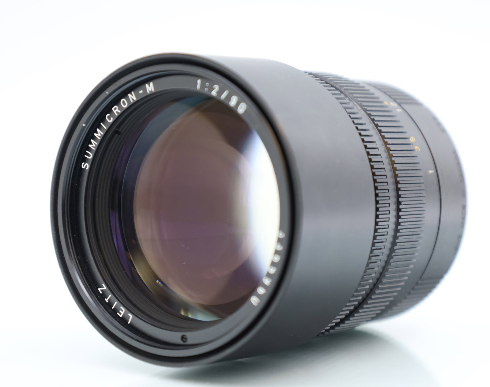 LEICA. Summicron-M. 1:2 / 90. Lens. M-Bajonett.: Circa 8,5 cm x 6,5 cm groß. Objektiv aus Metall. 90mm f/2. Leica M-Mount. Mechanik des Fokus- und Blendenrings geprüft. Sonnenblende ausziehbar. Minimale Gebrauchsspuren. Zustand siehe Fotos