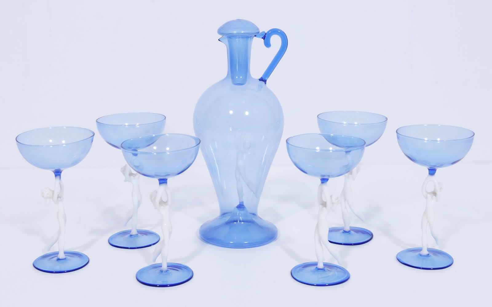 Fritz LAMPL (1892 - 1955). LAUSCHA BIMINI liqueur set. Art Deco. Austria.: Liqueur set consisting of 1 carafe (approx. 19 cm high) and 6 liqueur glasses (approx. 11 cm high). Blue and white glass with figurative stem in the shape of a female nude/dancer. Carafe with ovoid bo
