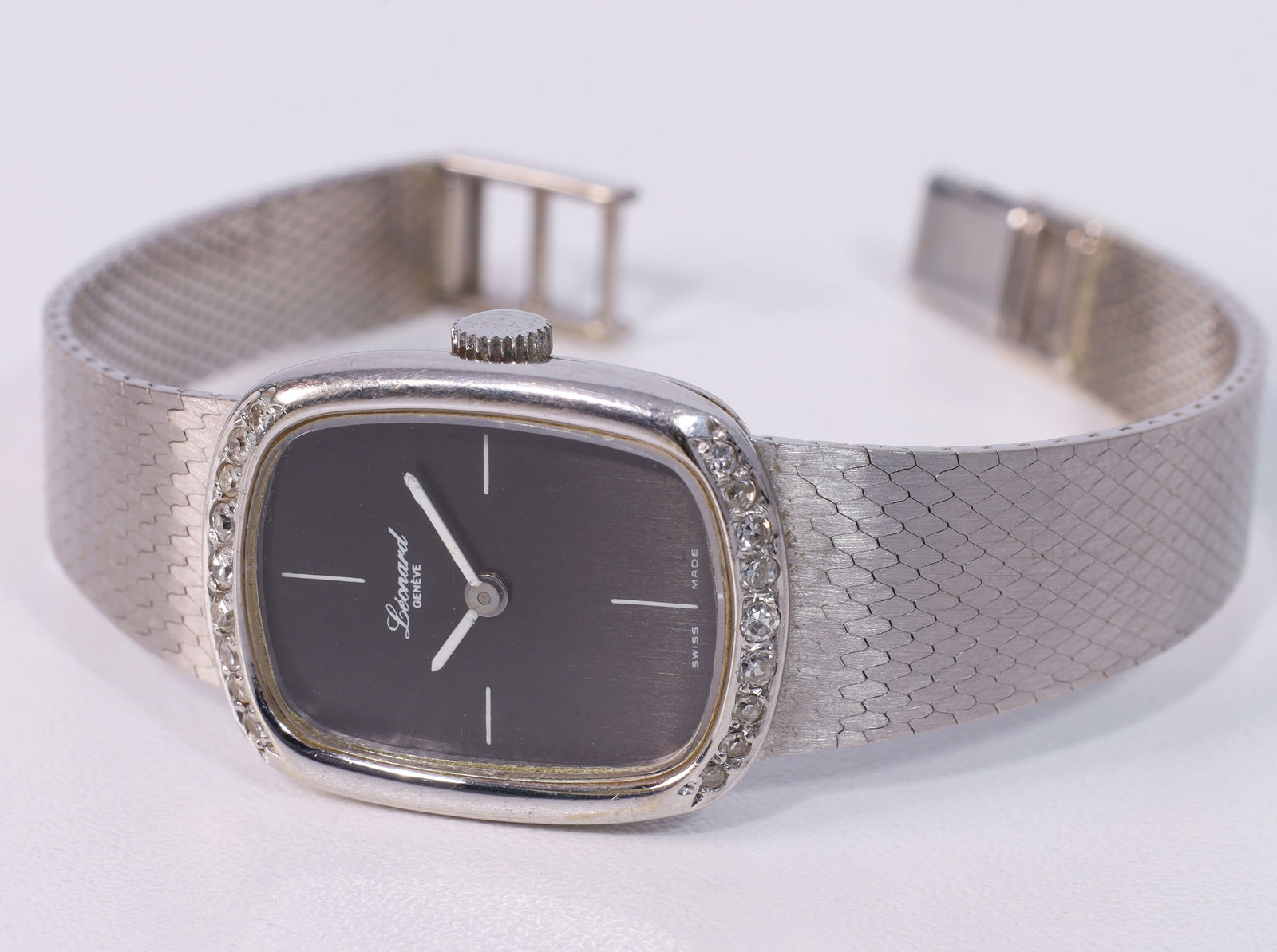 LEONARD. Ladies' wristwatch. Hand-wound. 585 white gold with diamonds.: Approx. 33.7 grams total weight. Approximately 25 mm x 20 mm case. Bezel decorated with a total of 18 very small diamonds. Black dial with 4 markers. Hallmarked: fineness. Movement runs. Accuracy not
