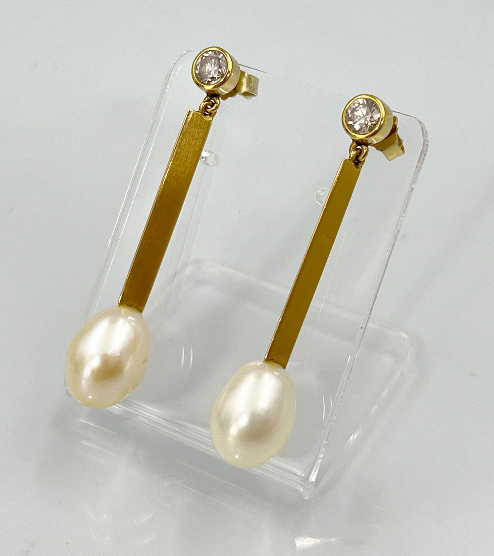 Pair of earrings. 750 yellow gold with diamonds and pearls.: Total weight approx. 7.7 grams. 2 rod-shaped stud earrings with pearl and diamond setting. Diamonds totalling 0.60 ct. These are of lower colour and medium clarity. Hallmarked: fineness. Gold tested.