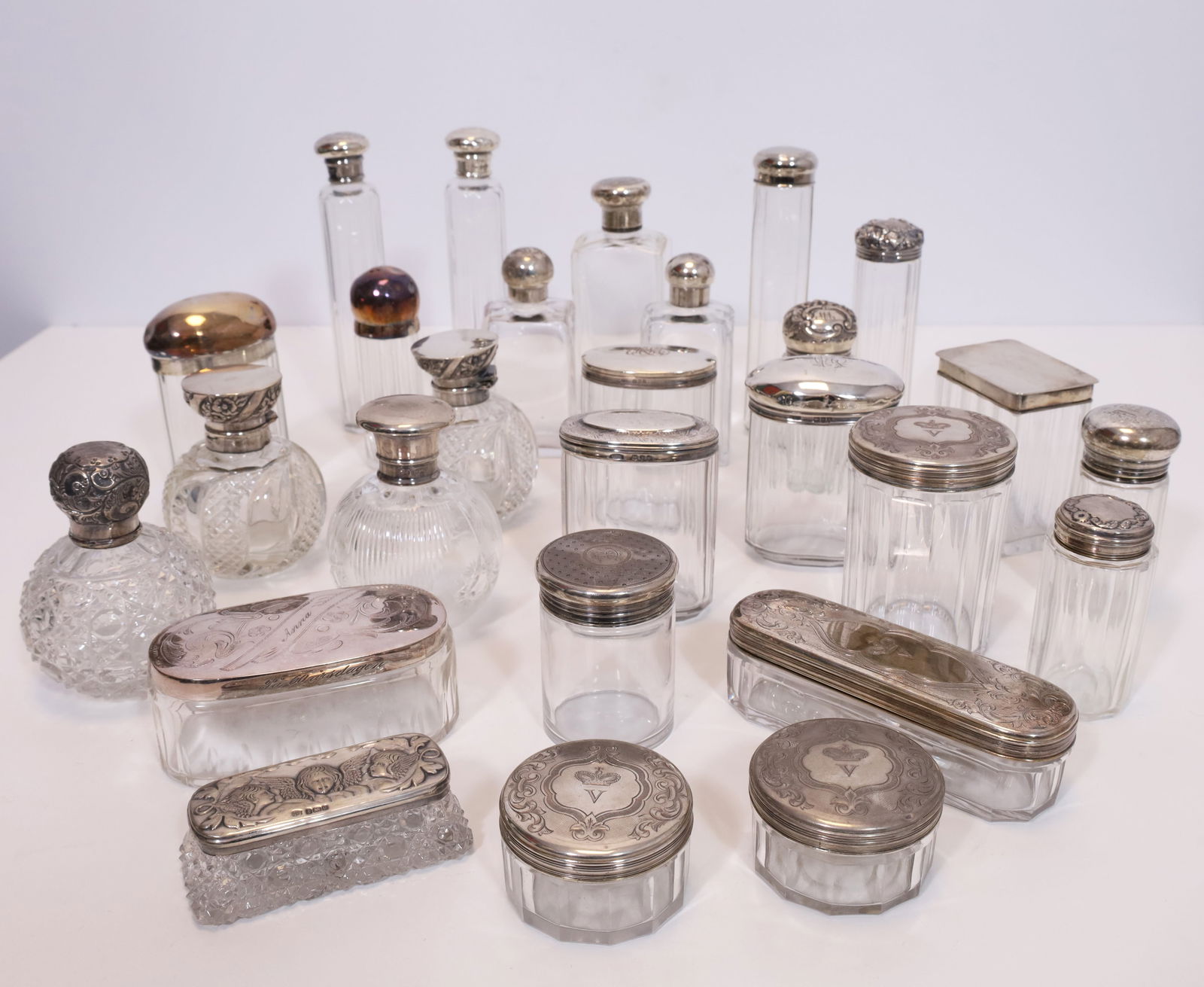 Set of 27 crystal glass vessels with silver lids. Mostly England.: Various shapes and sizes. Some with relief decorations, some with initials. Various alloys. Not tested. Condition as shown in photos.
