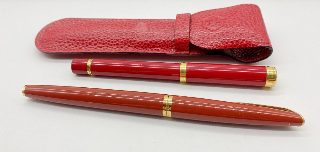 Two Vintage Waterman Fountain Pins in Original Case: to include one brown body pin with 18k nib and one red body pen. Comes with Waterman vinyl holder.