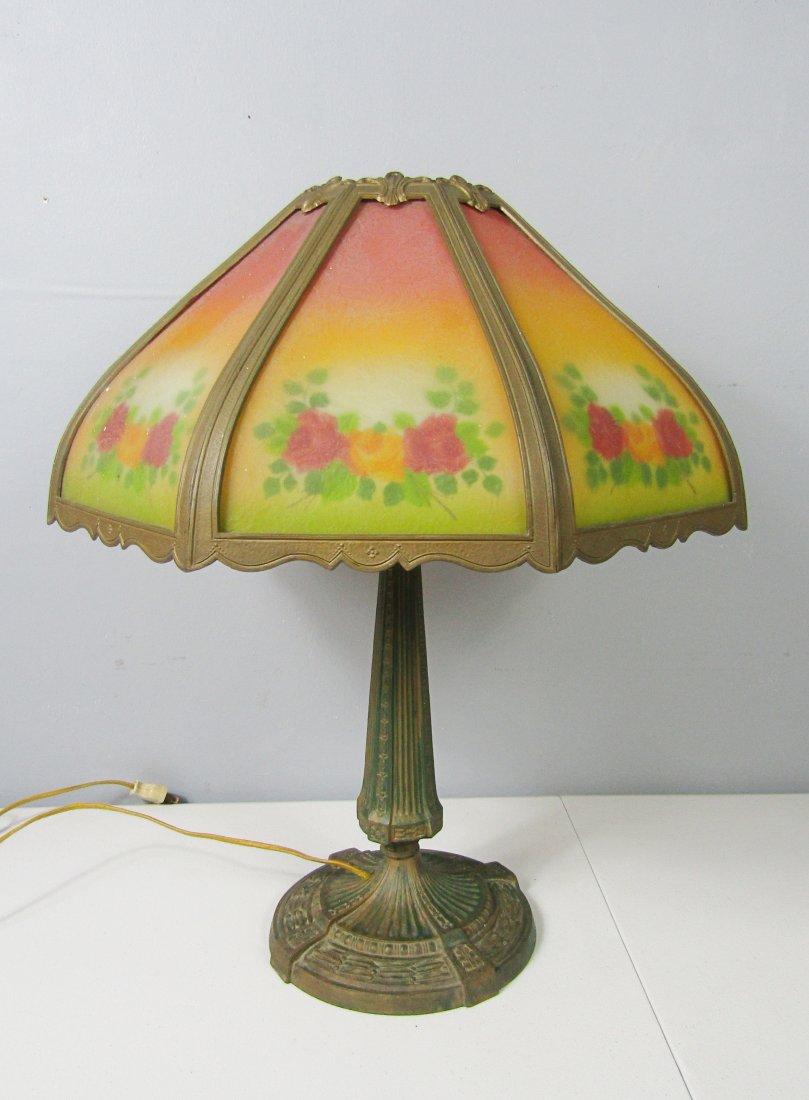 antique table lamp with reverse painted bent shades: Impressive antique table lamp. stands 22" high. bent, reverse painted glass panels with flower pattern. shade measures 18" in diameter. the shade sits on a metal base with green verdigris. nice patter