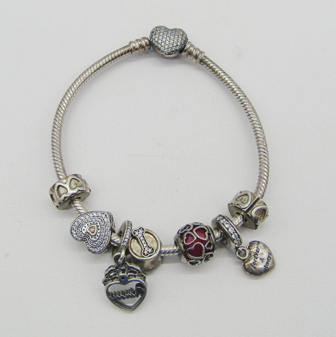 Pandora sterling cable charm bracelet with 7 charms: sterling cable charm bracelet by Pandora with 7 charms. heart shape clasp. weighs 35 grams.