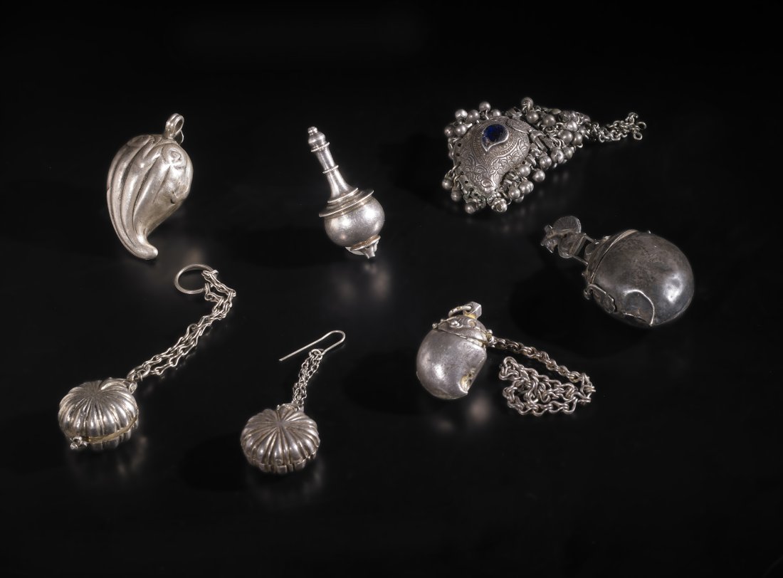 Seven silver pendants India, XIX secolo. Weight: 139 grams: lot composed of three mango fruit shaped pendant boxes, two small circular pill boxes, a small sprinkler and a pendant also in the shape of a mango