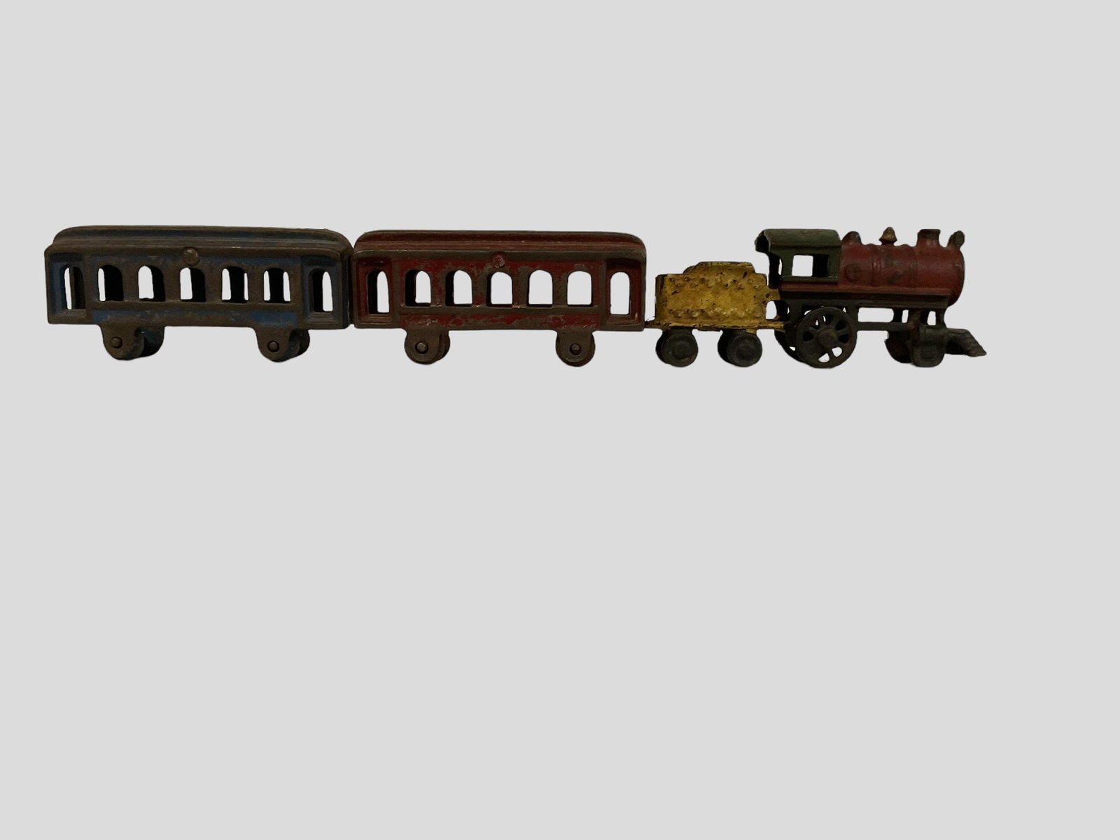 3 Piece Cast Iron Train Set Engine and Tender Car Passenger Cars: 3 Piece Cast Iron Train Set Engine and Tender Car and 2 Passenger Cars, Engine measures 5 1/2" L, Passenger cars measure 4 1/2" L, Condition, wear age appropriate, paint chips, rust, see photographs