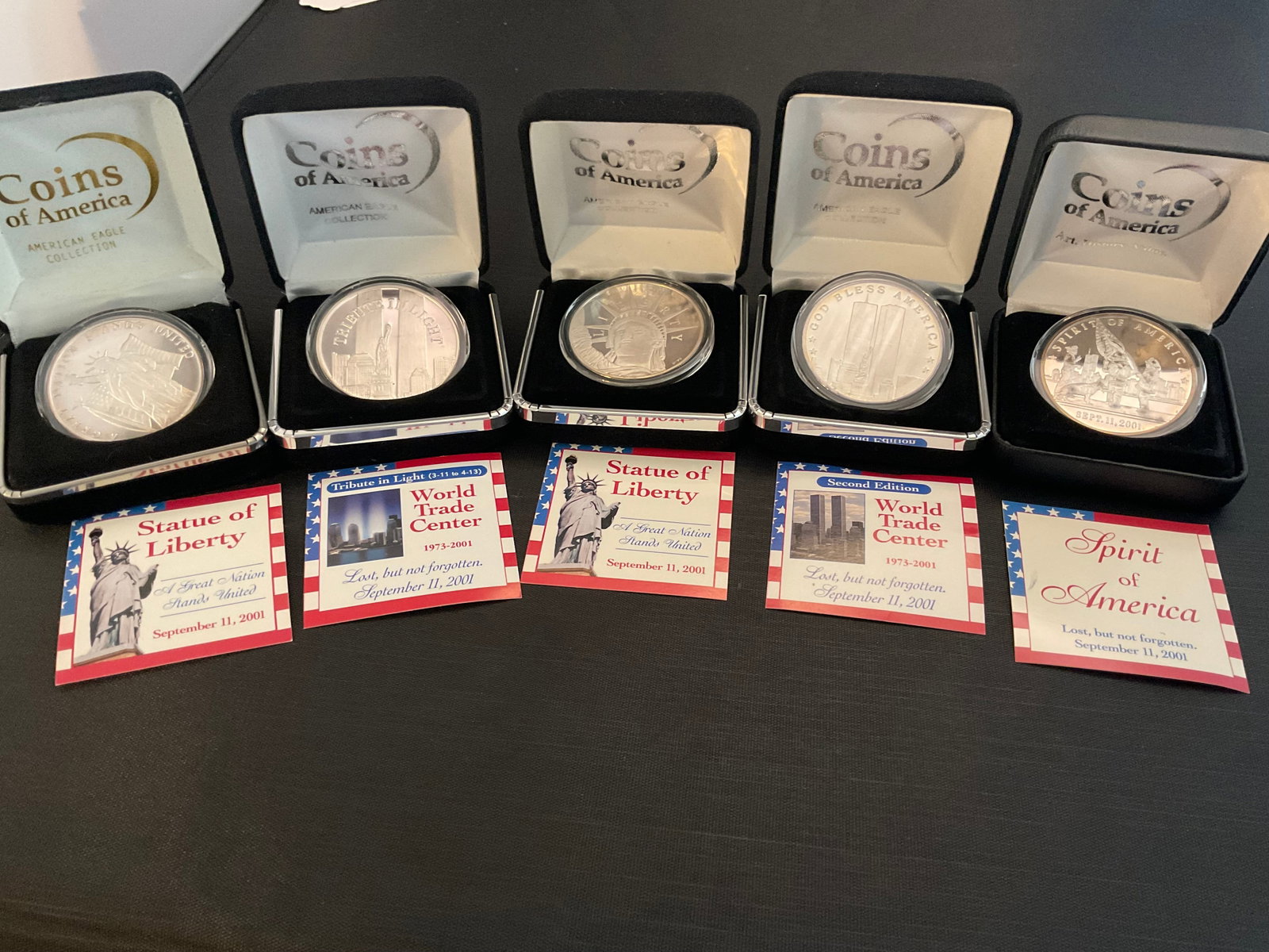 Group of 5 1-ozt 0.999 Fine Silver Coins of America: Group of 5 1-ozt 0.999 Fine Silver Coins of America, Statue of Liberty, World Trade Center, Liberty, World Trade Center, and Spirit of America, in display cases, Condition, see photographs.